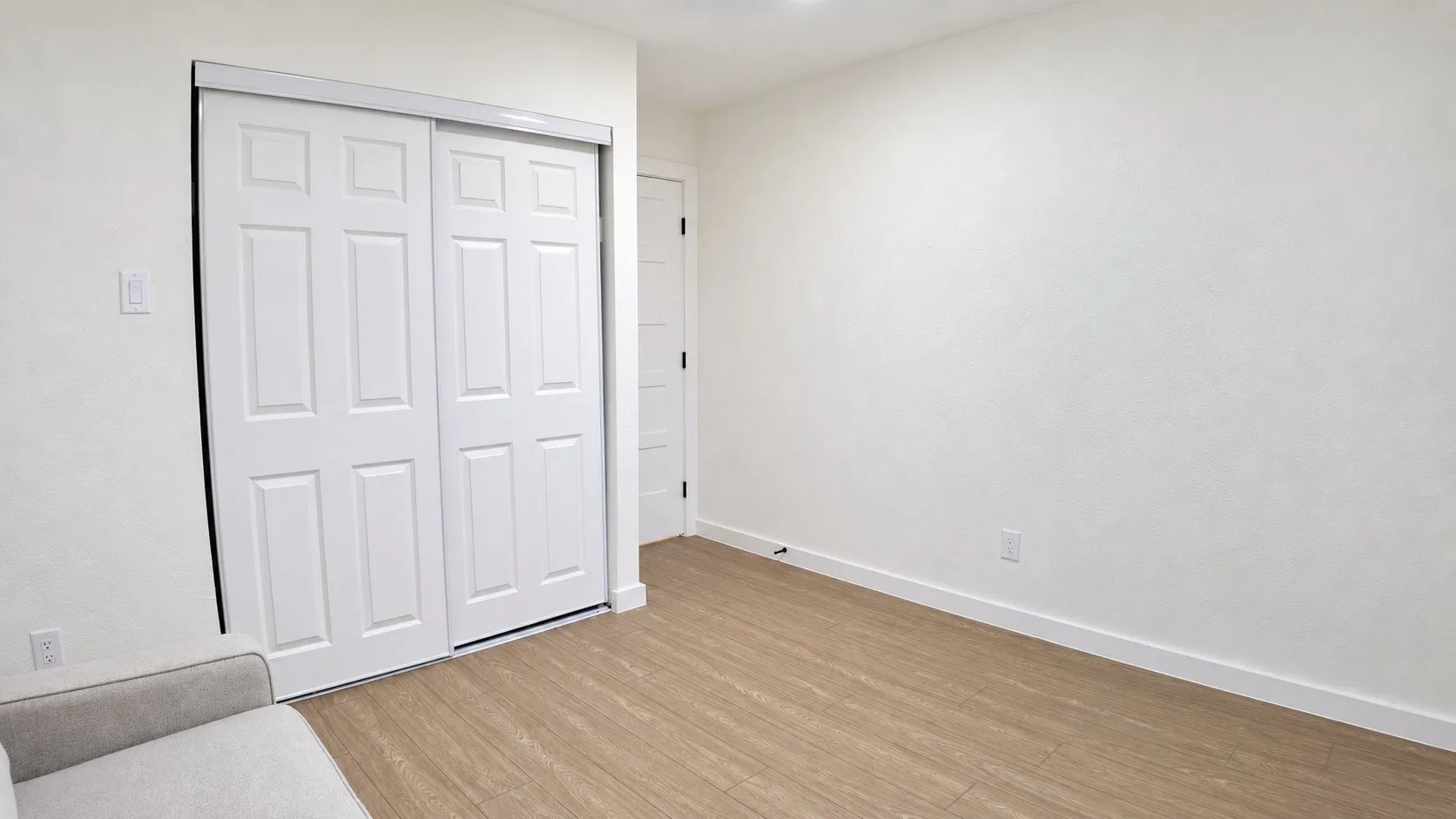 Light wood-finish flooring, white walls, and a white six-panel sliding closet door
