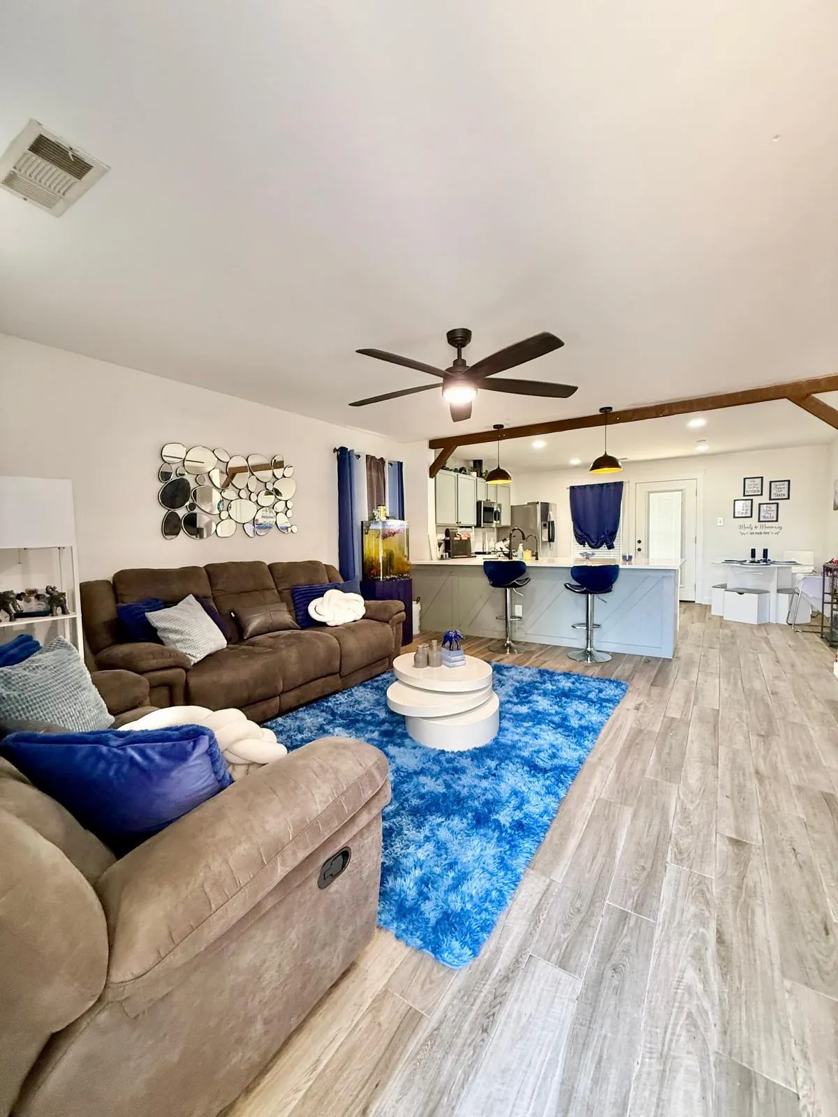 Open-concept living space featuring wood-finish flooring, a ceiling fan with integrated lighting, and recessed lighting