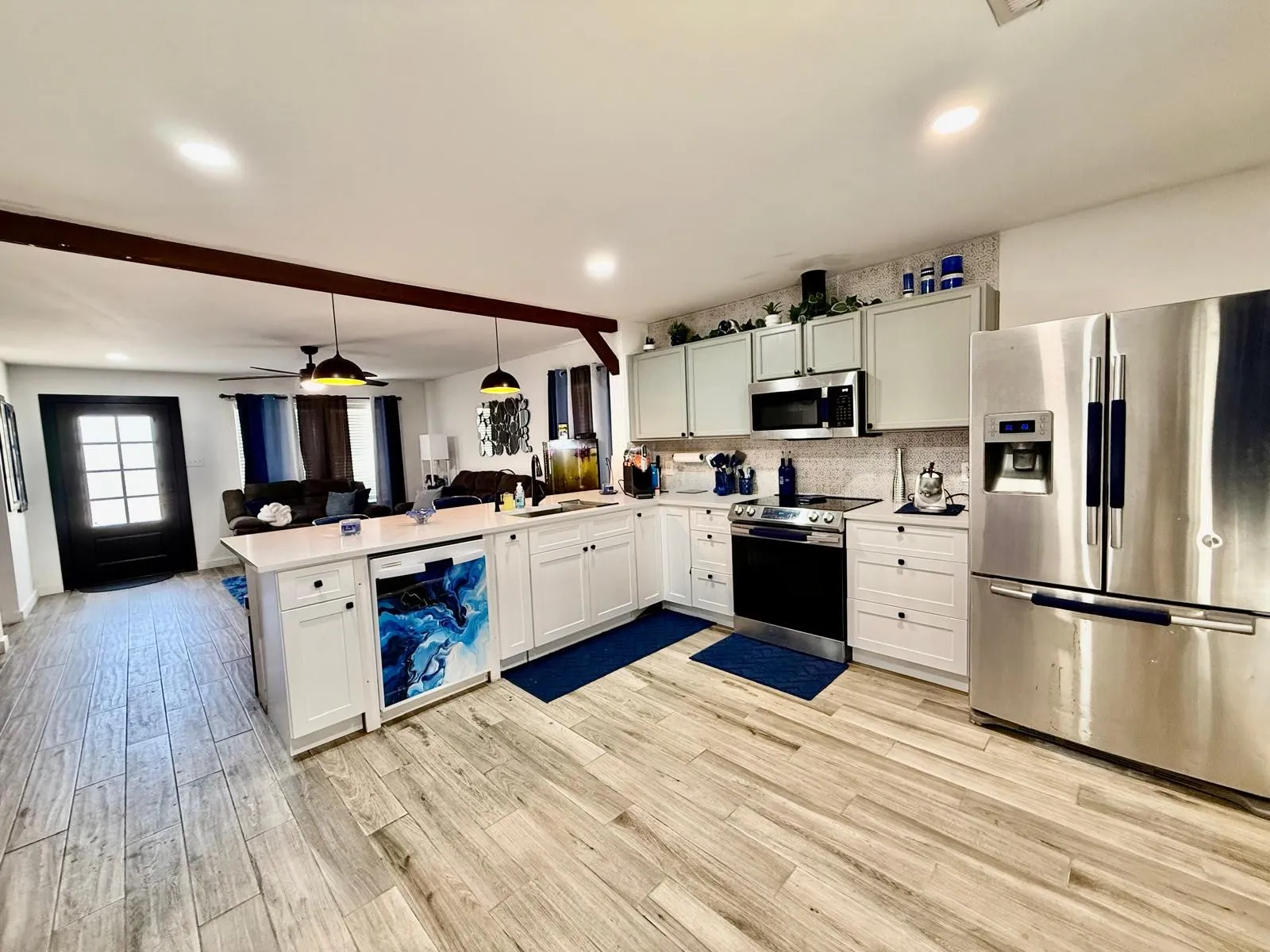 Kitchen featuring a central island, stainless steel appliances, wood-finish flooring, white cabinetry, and recessed lighting