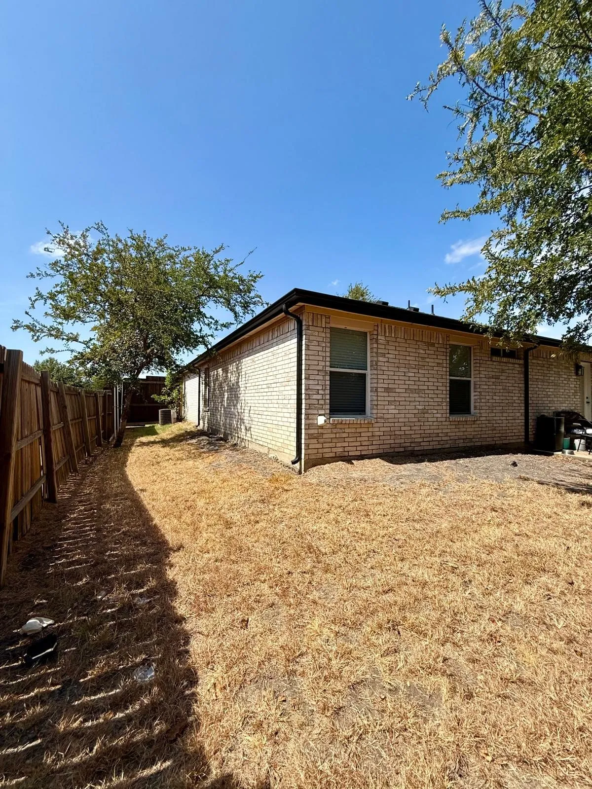 Brick exterior with multiple windows and a privacy fence