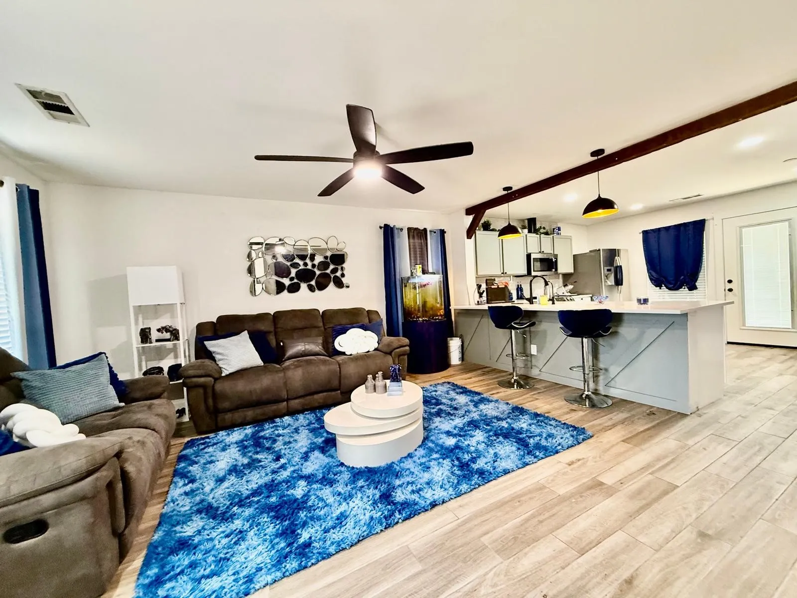Open-concept living area featuring wood-finish flooring, a contemporary ceiling fan, and a kitchen island with pendant lighting