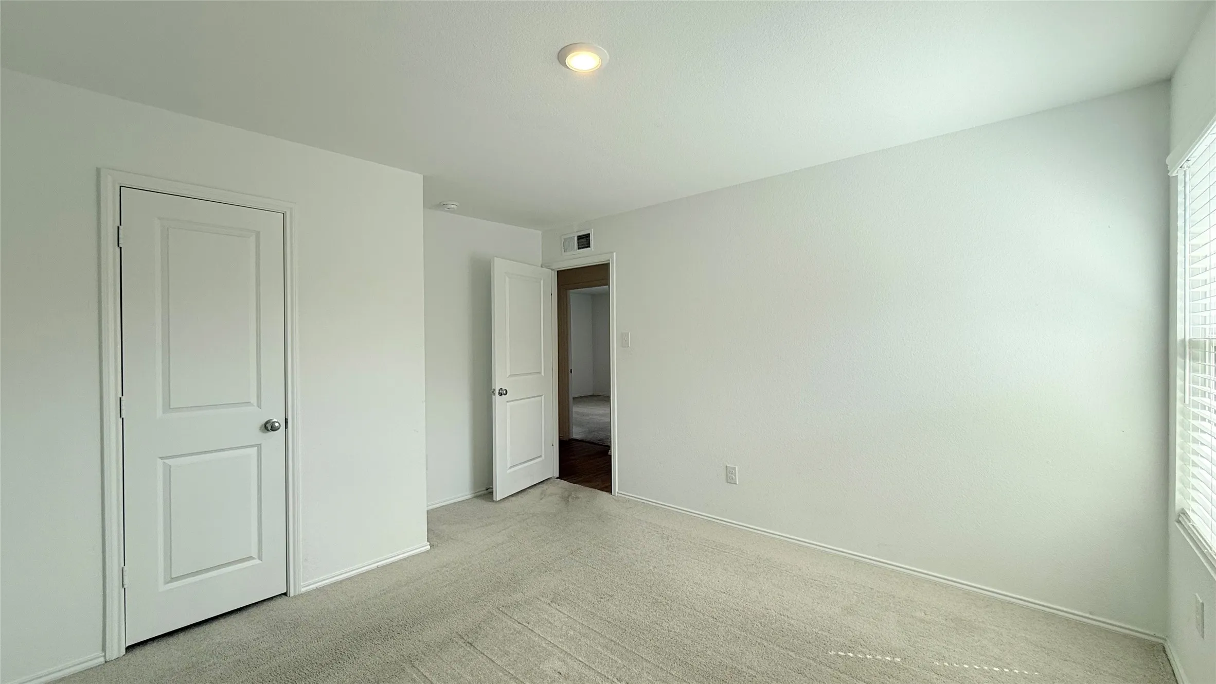 Recessed ceiling lighting, light-toned carpeting, white interior doors, and a window with blinds