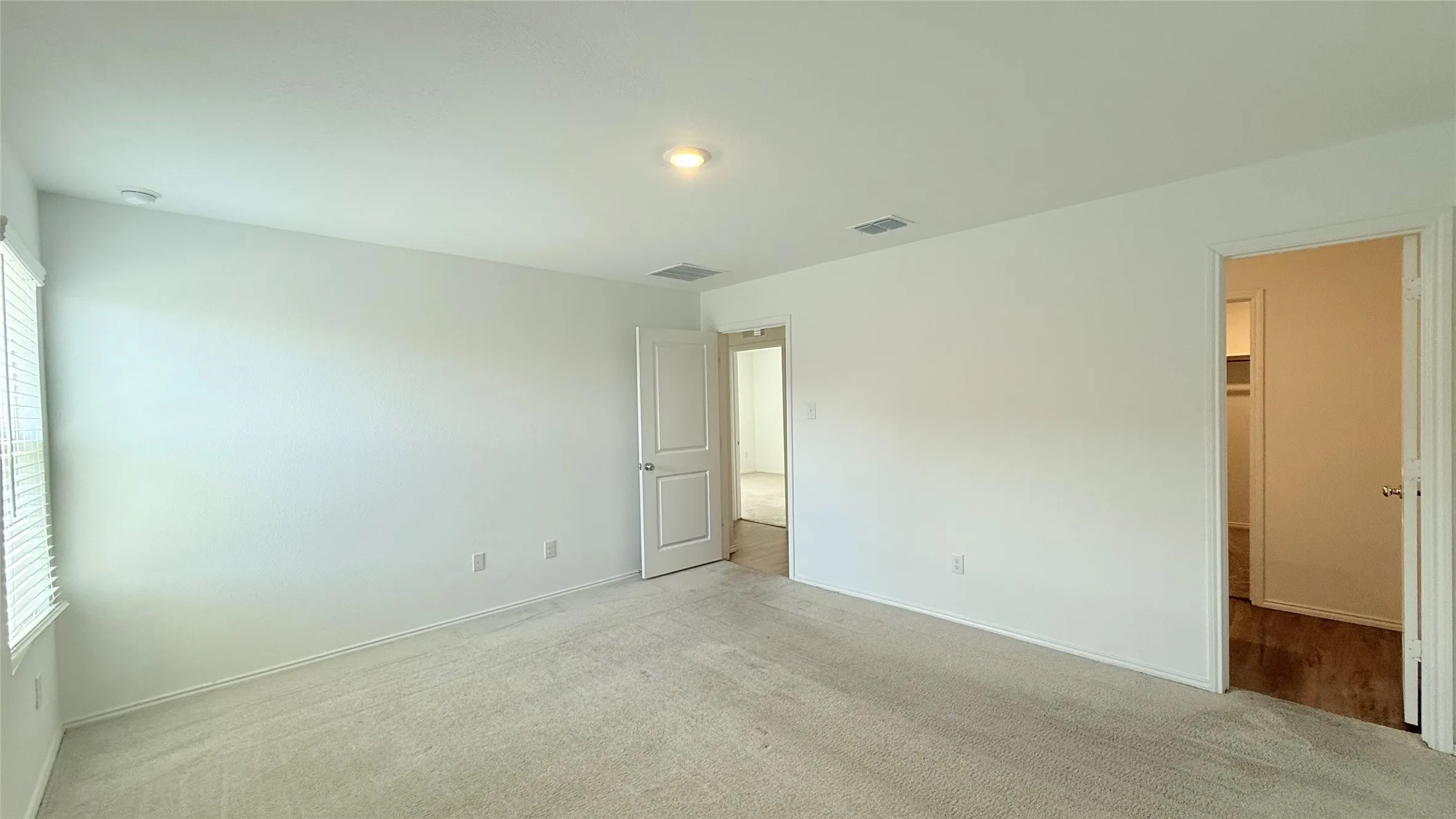 Bright interior with neutral carpeting, recessed lighting, and white paneled doors