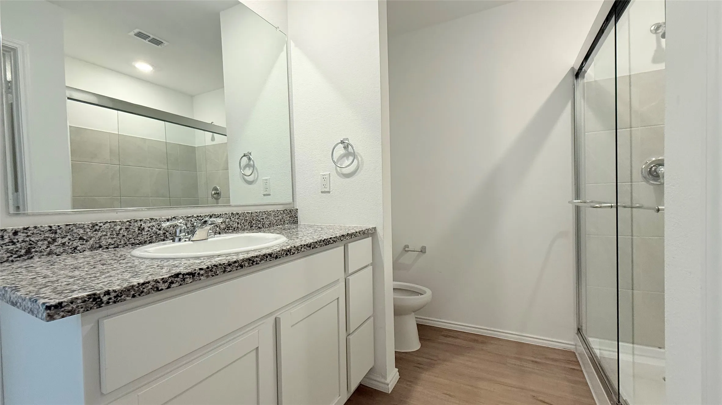 Vanity with granite-style countertop, white cabinetry, and undermount sink
