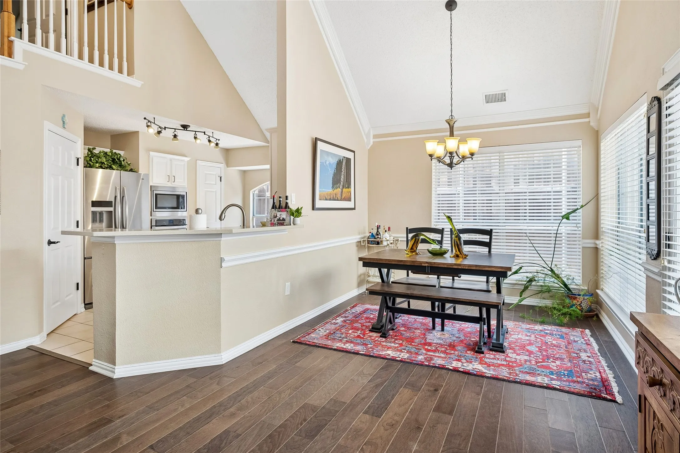 Open-concept living area featuring wood-finish flooring, vaulted ceilings, and a kitchen pass-through with a breakfast bar