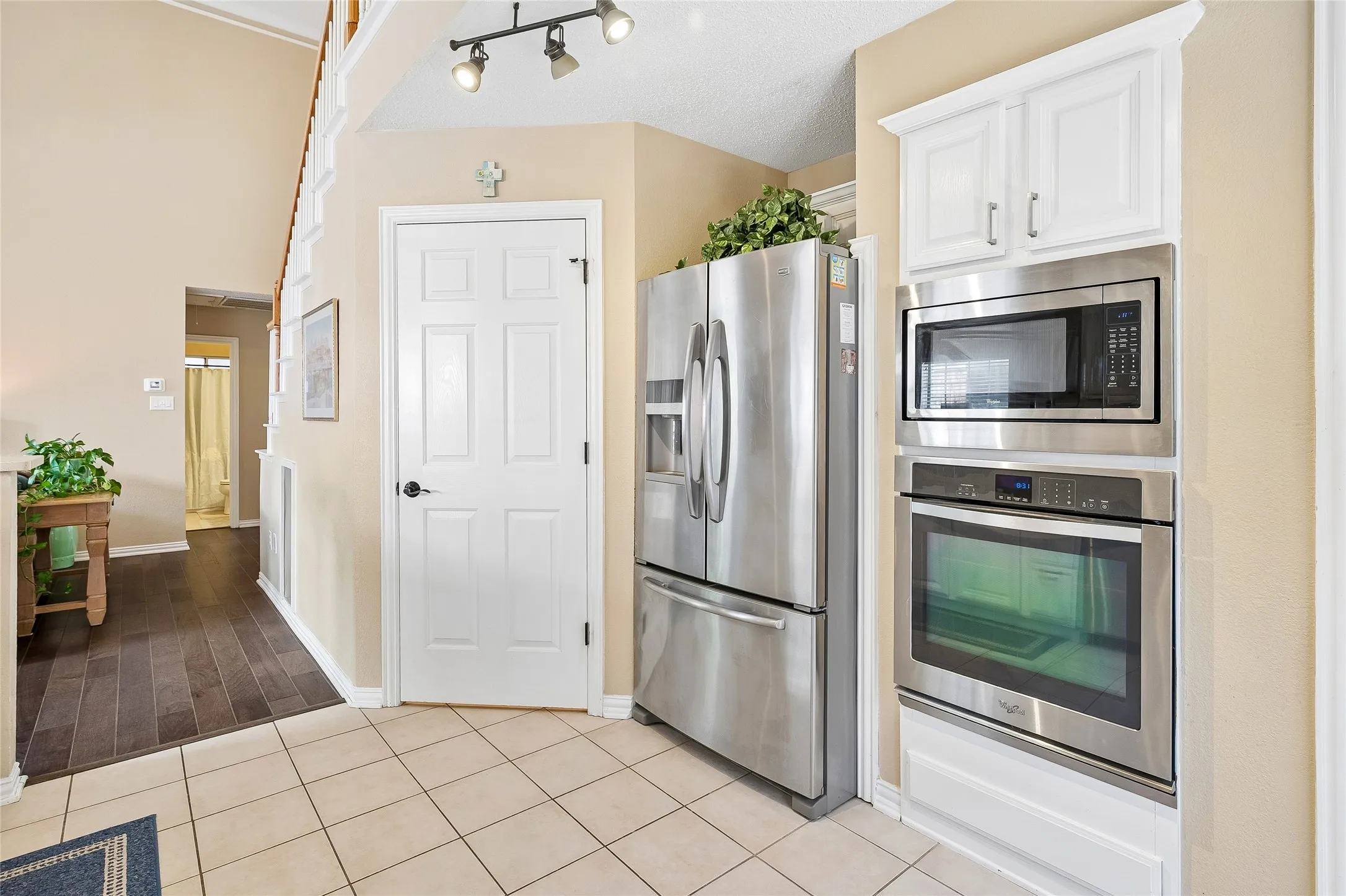 Stainless steel appliances, including a built-in microwave and oven, are integrated into white cabinetry