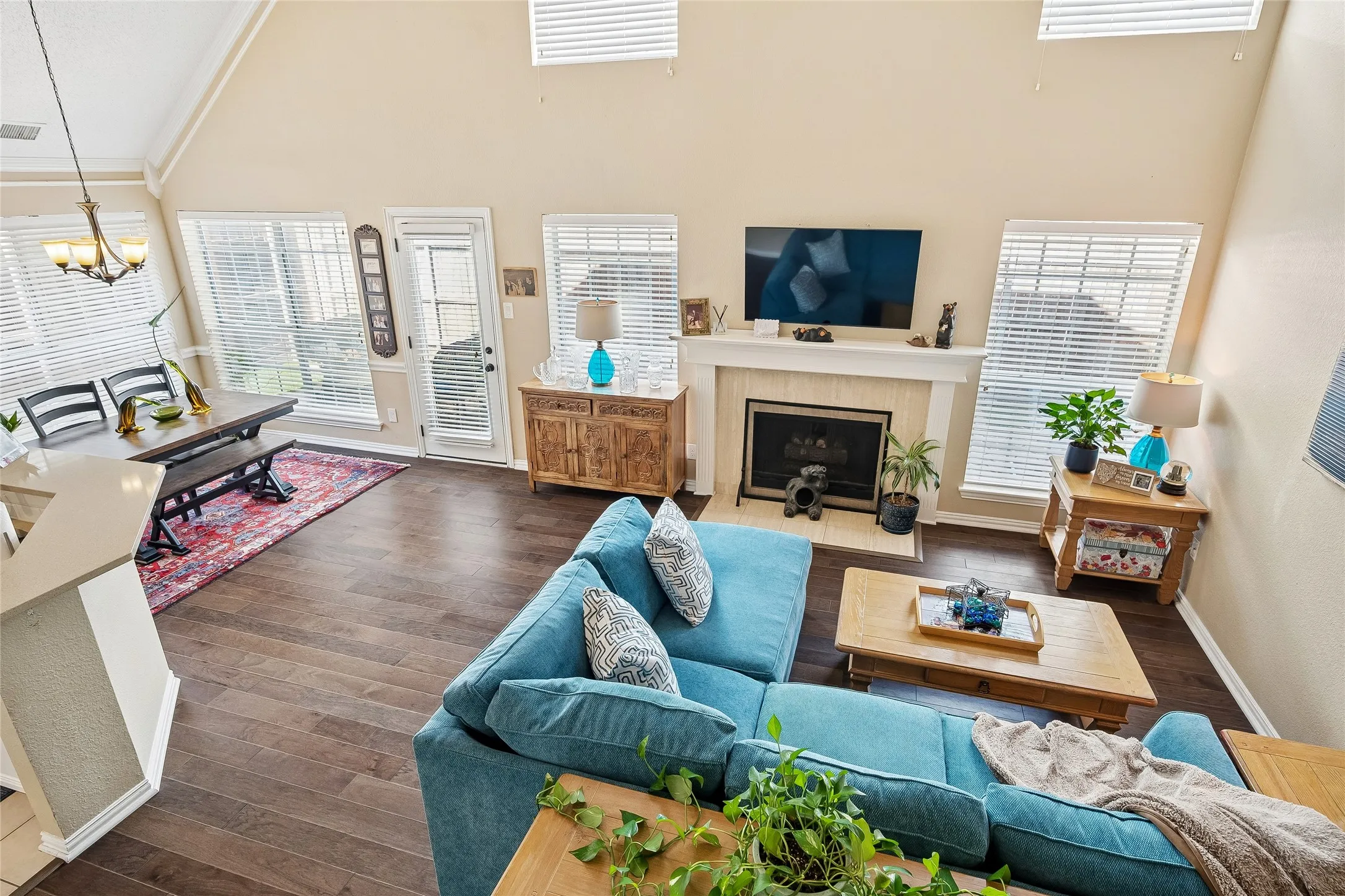 Open-concept living space featuring wood-finish flooring, a vaulted ceiling, and a fireplace with a mantel