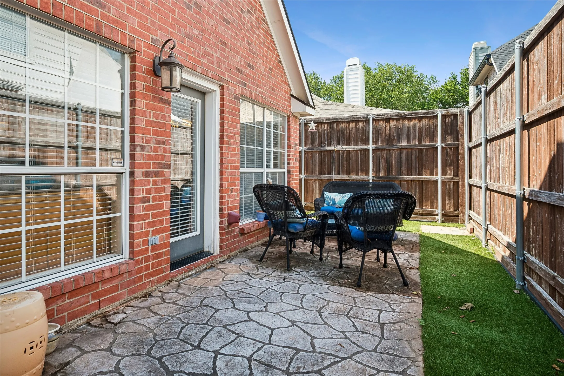 Private outdoor patio featuring a stamped concrete surface, brick exterior, and a privacy fence
