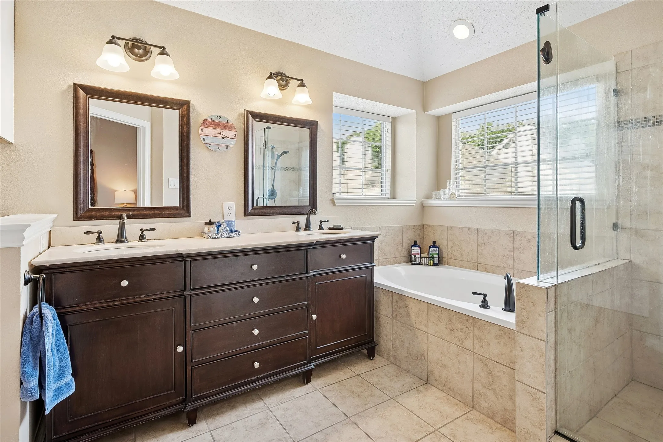 Dual vanity with dark wood-finish cabinetry and light-colored countertops, featuring two framed mirrors and sconce lighting