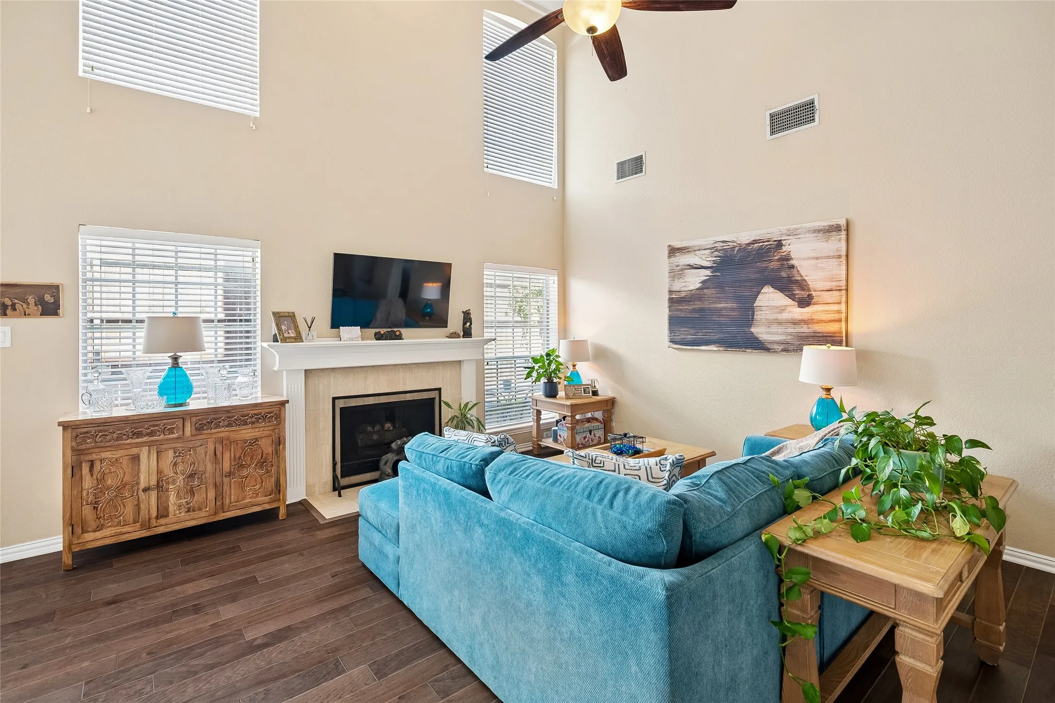 Living area featuring a soaring ceiling, wood-finish flooring, and a fireplace with a mantel