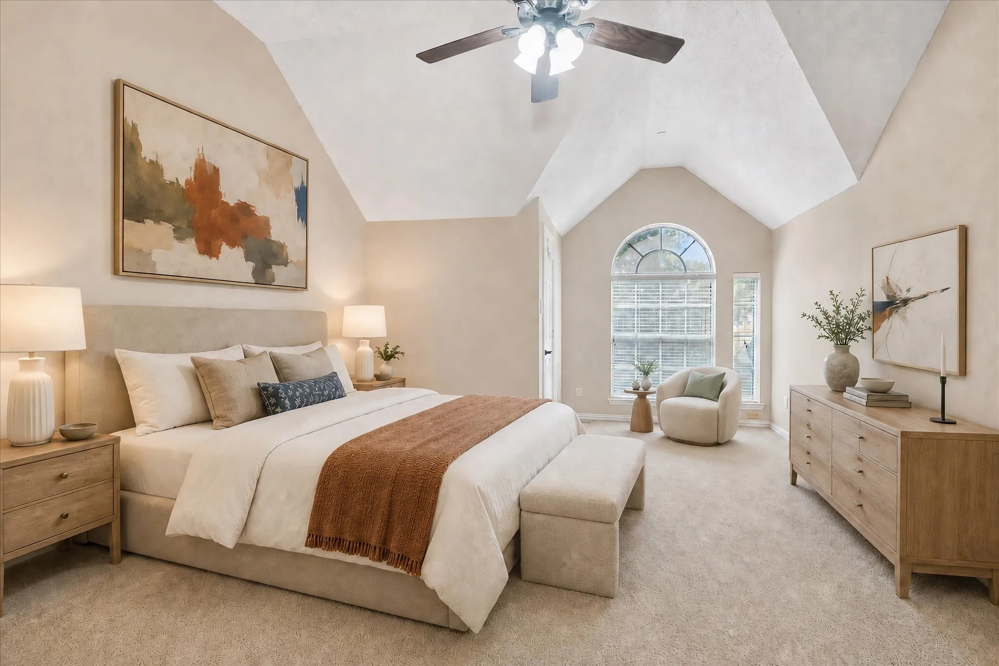 Primary, spacious bedroom featuring vaulted ceilings, an arched window, and plush carpeting- *digital staging*