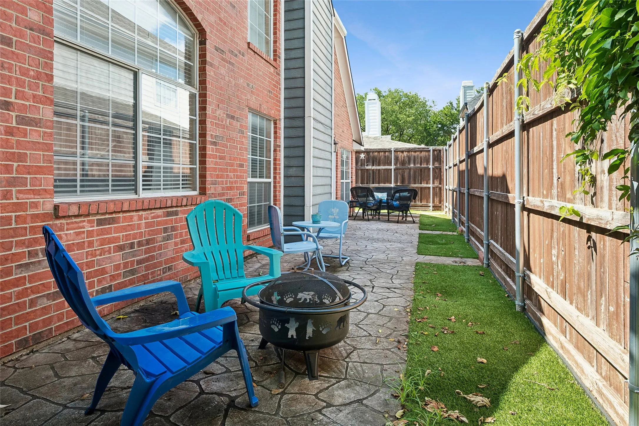 Patio space featuring stamped concrete, a privacy fence, and a brick exterior