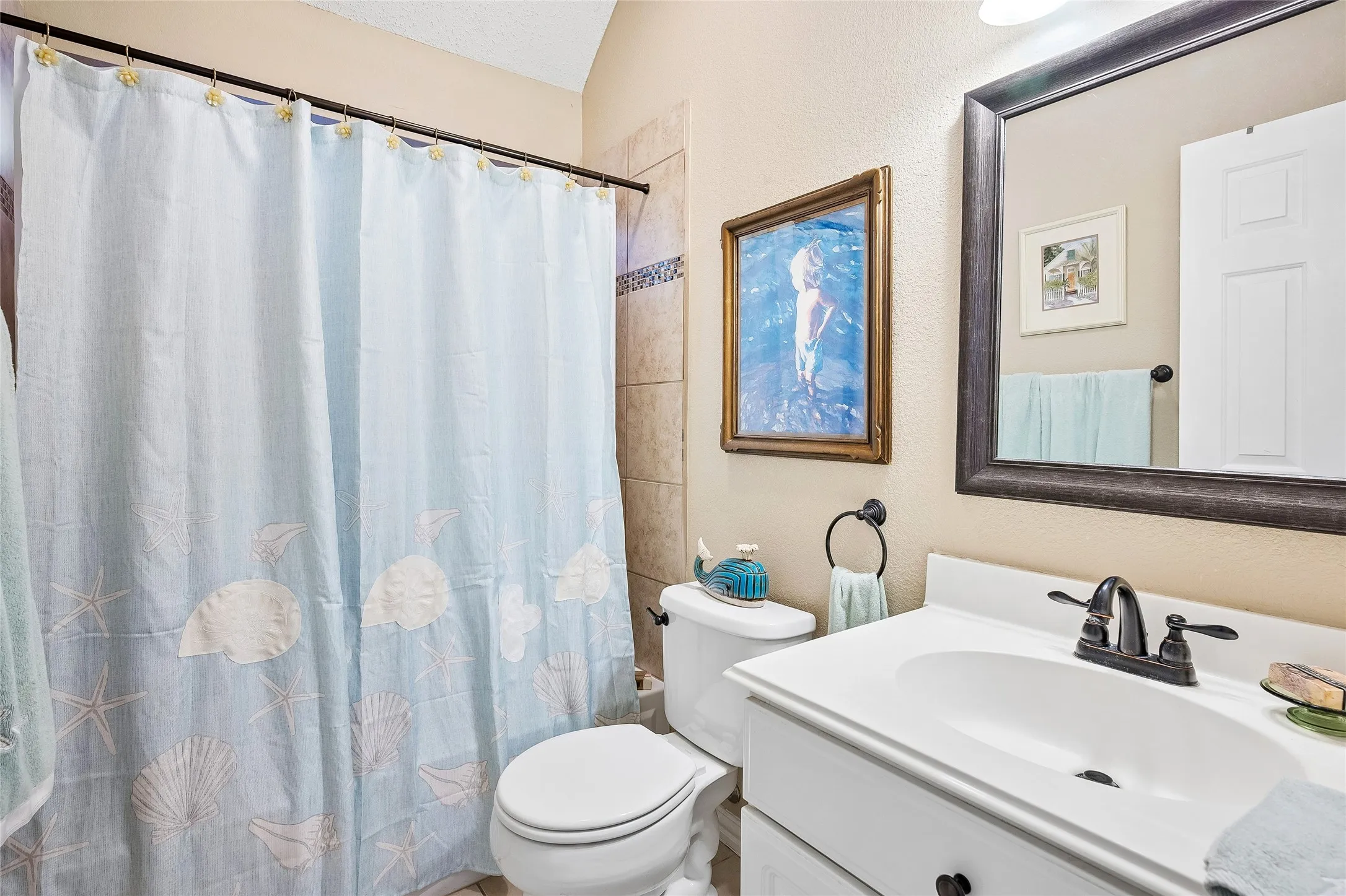 Bathroom featuring a white vanity with a single basin sink, dark bronze-finish fixtures, and a framed mirror