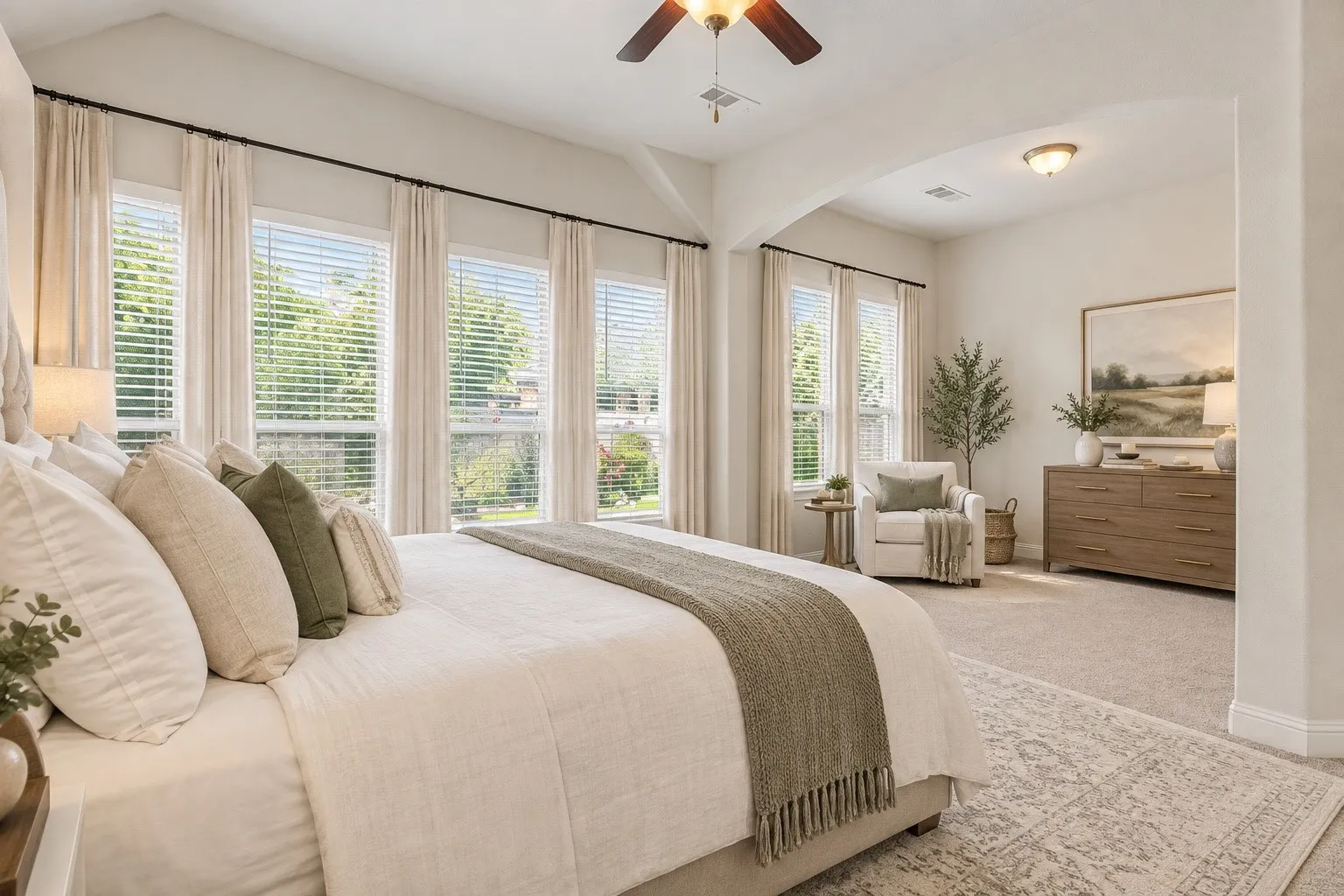 *virtually staged* Vaulted ceiling with ceiling fan, multiple windows with blinds and drapes, arched entryway, and neutral carpeting