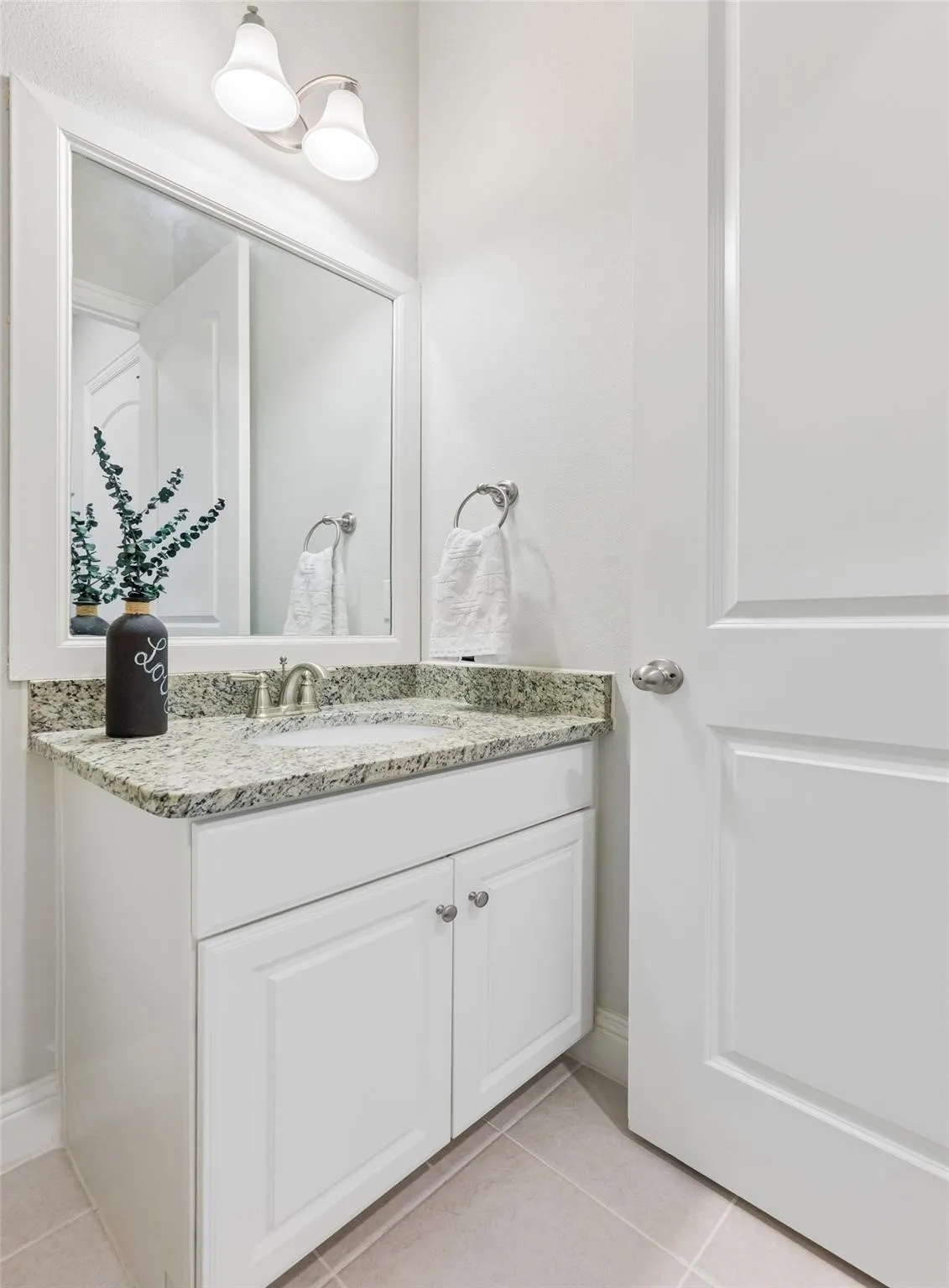 White vanity with shaker-style cabinet doors, brushed nickel hardware, and an undermount sink