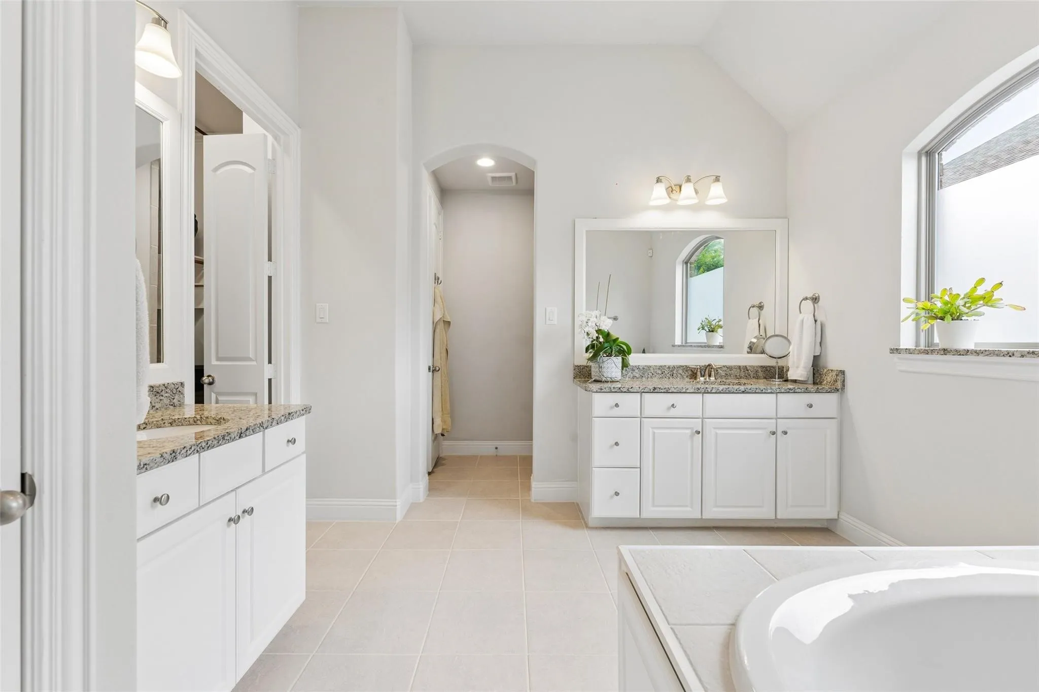Dual vanity sinks with granite countertops and white cabinetry