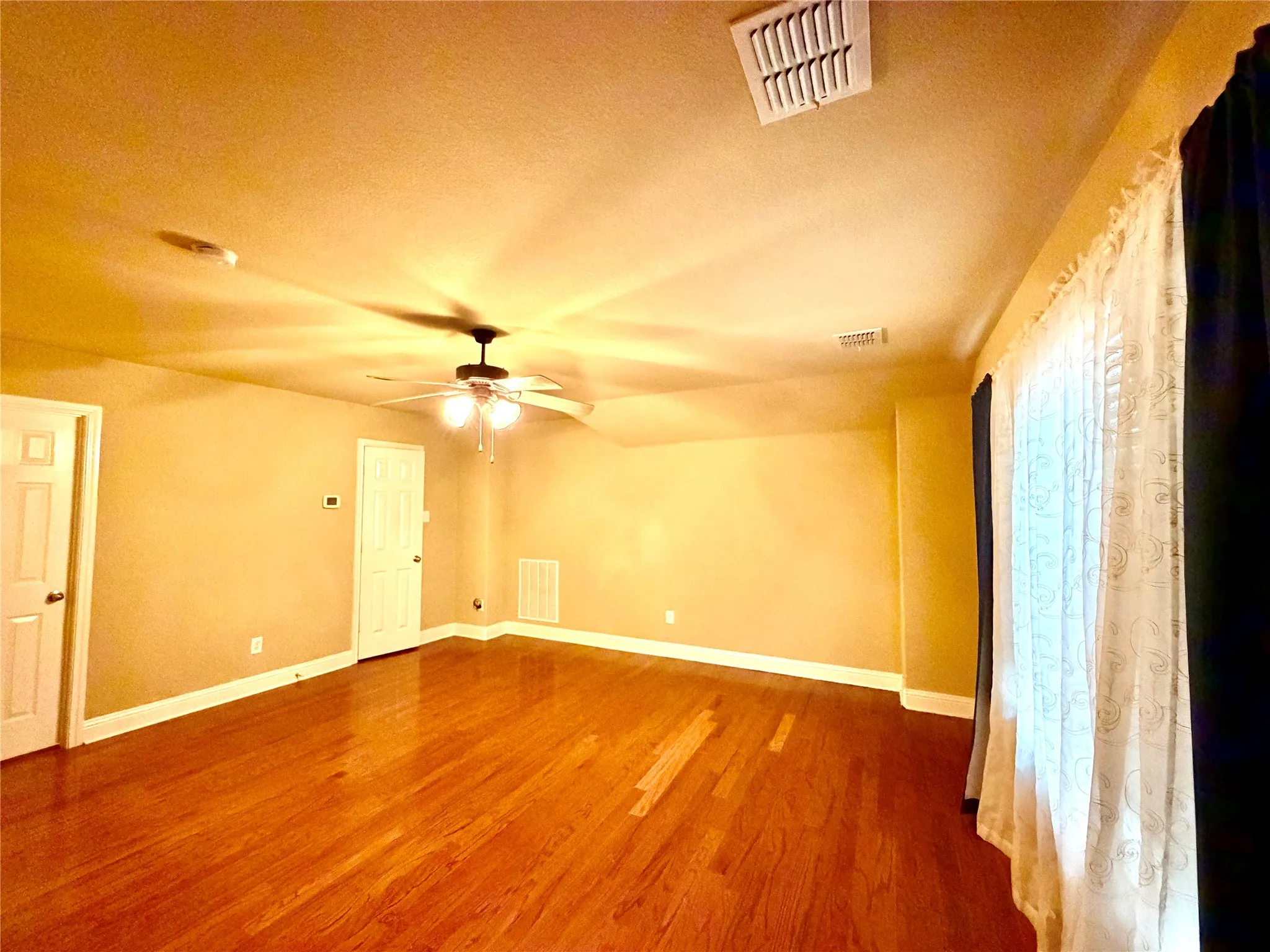 Wood-finish flooring throughout, ceiling fan with integrated lighting, and multiple panel doors