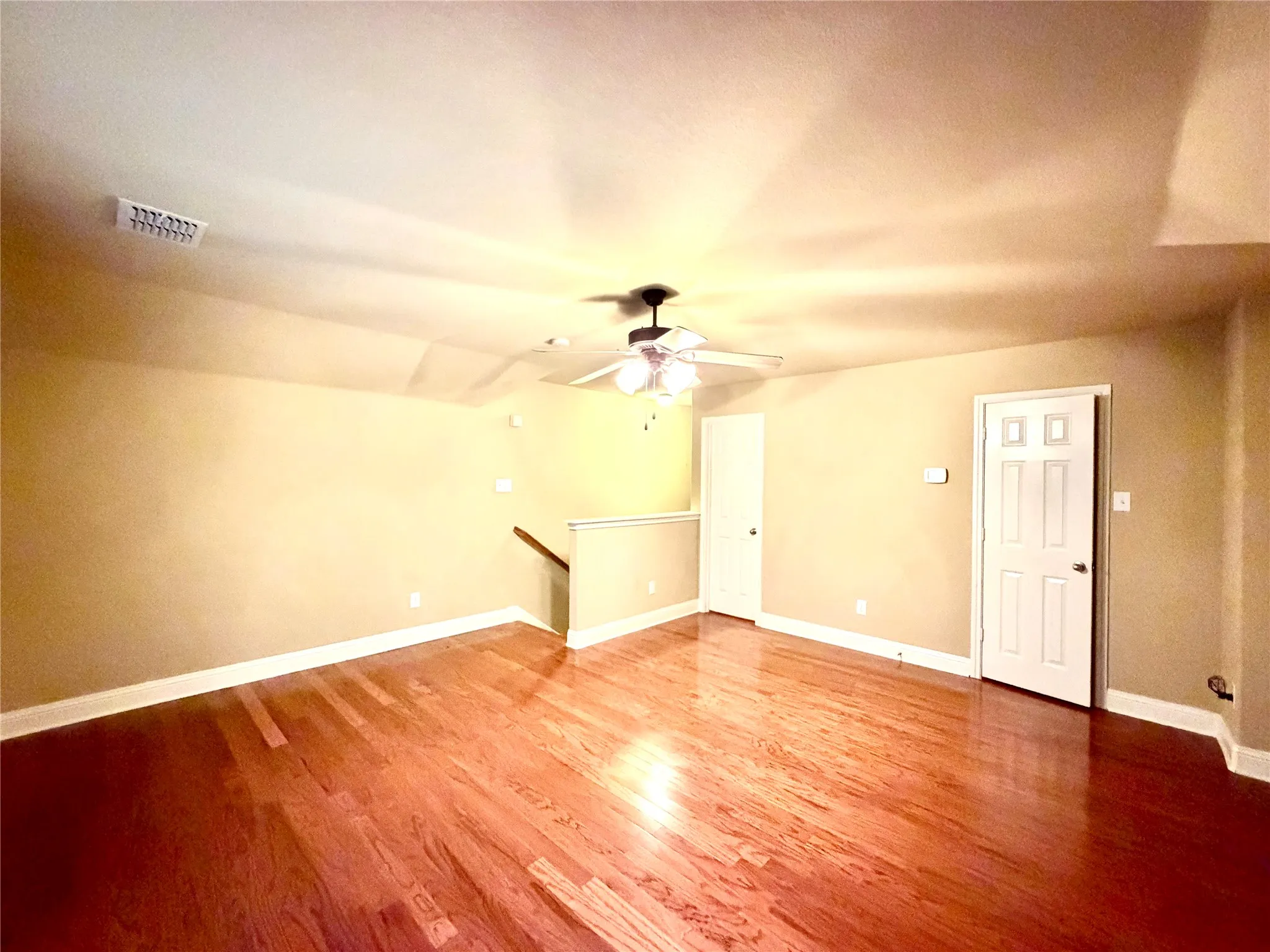 Hardwood flooring, painted walls, white trim, white paneled door, and a ceiling fan with integrated lighting
