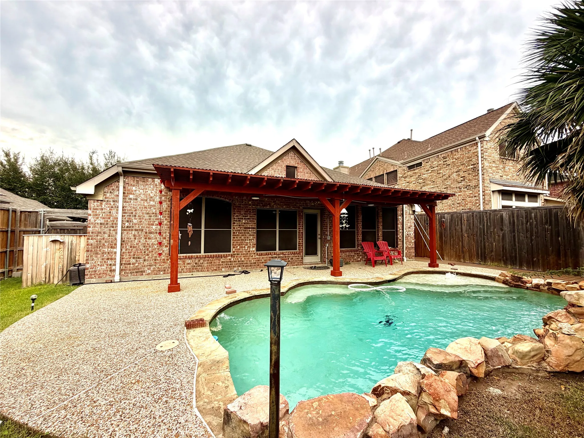 Brick exterior with a covered patio and a built-in swimming pool