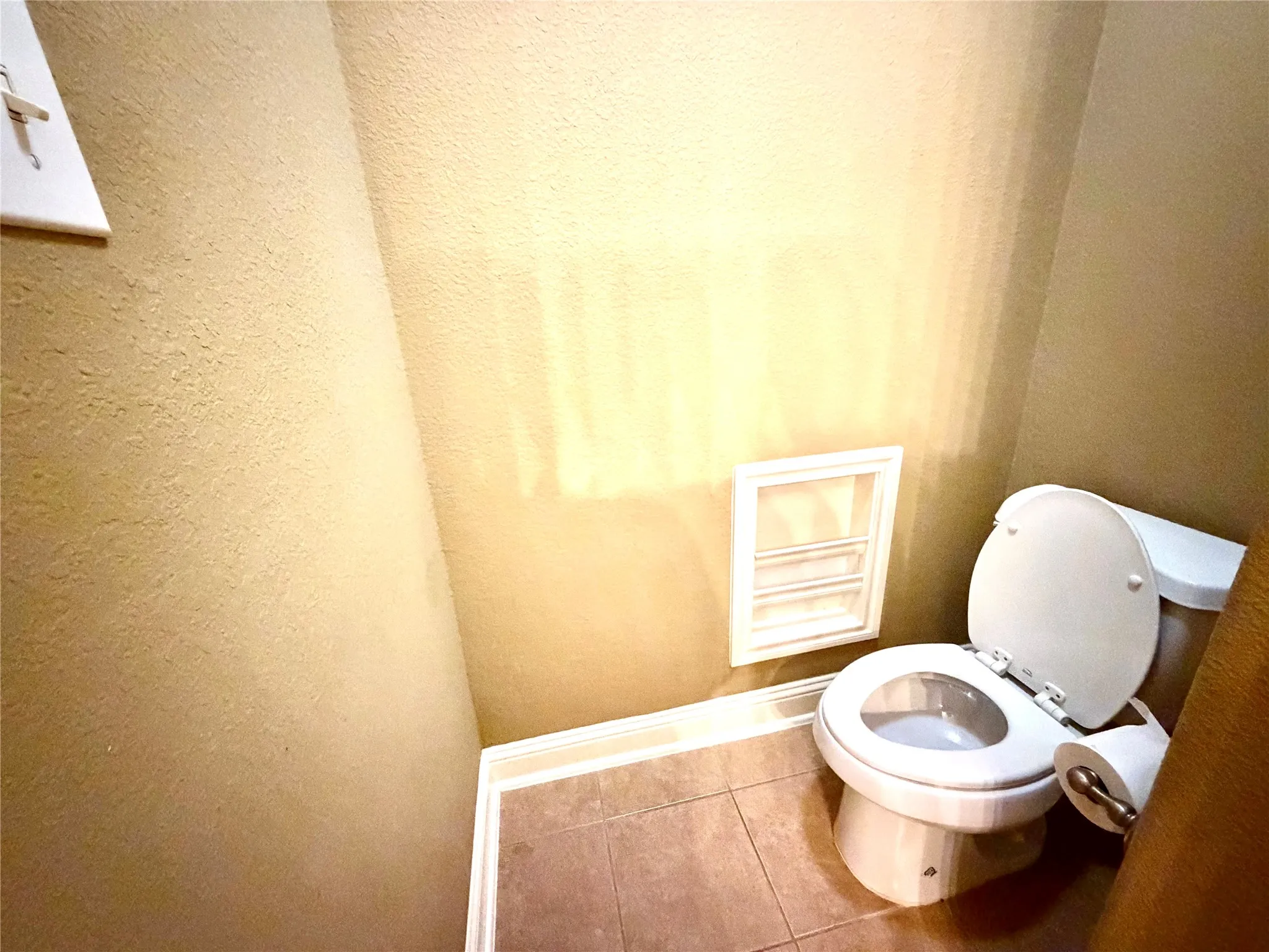 Recessed wall storage, ceramic tile flooring, and a white toilet fixture