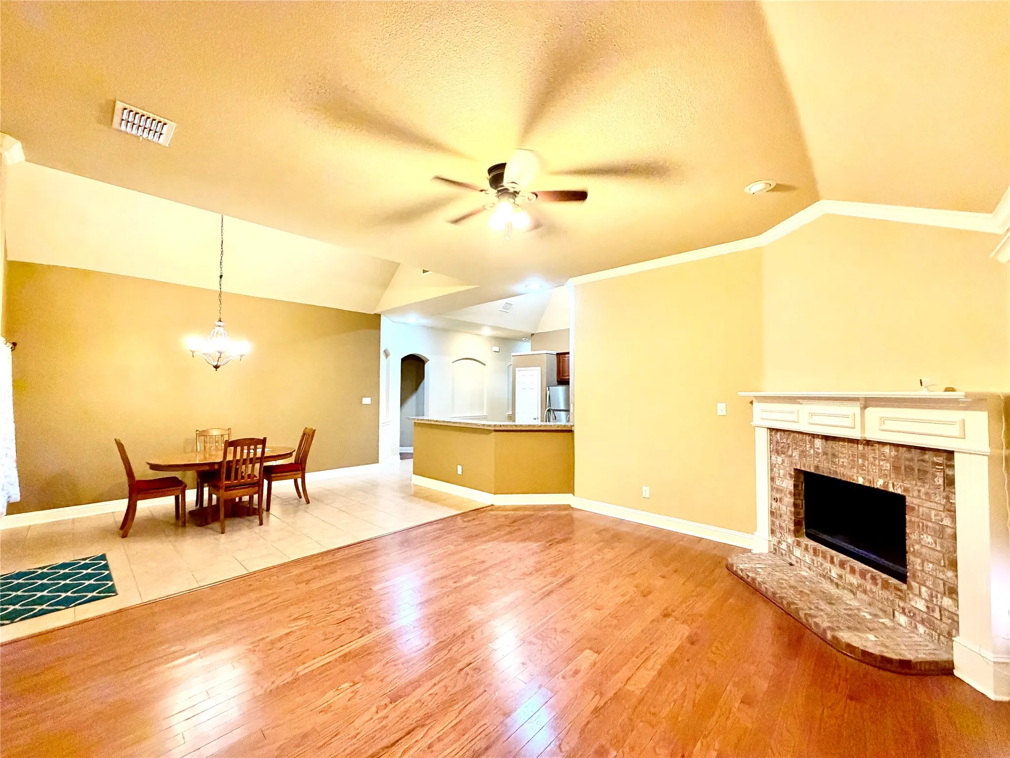 Living area featuring wood-finish flooring, a brick-surround fireplace with mantel, and a ceiling fan