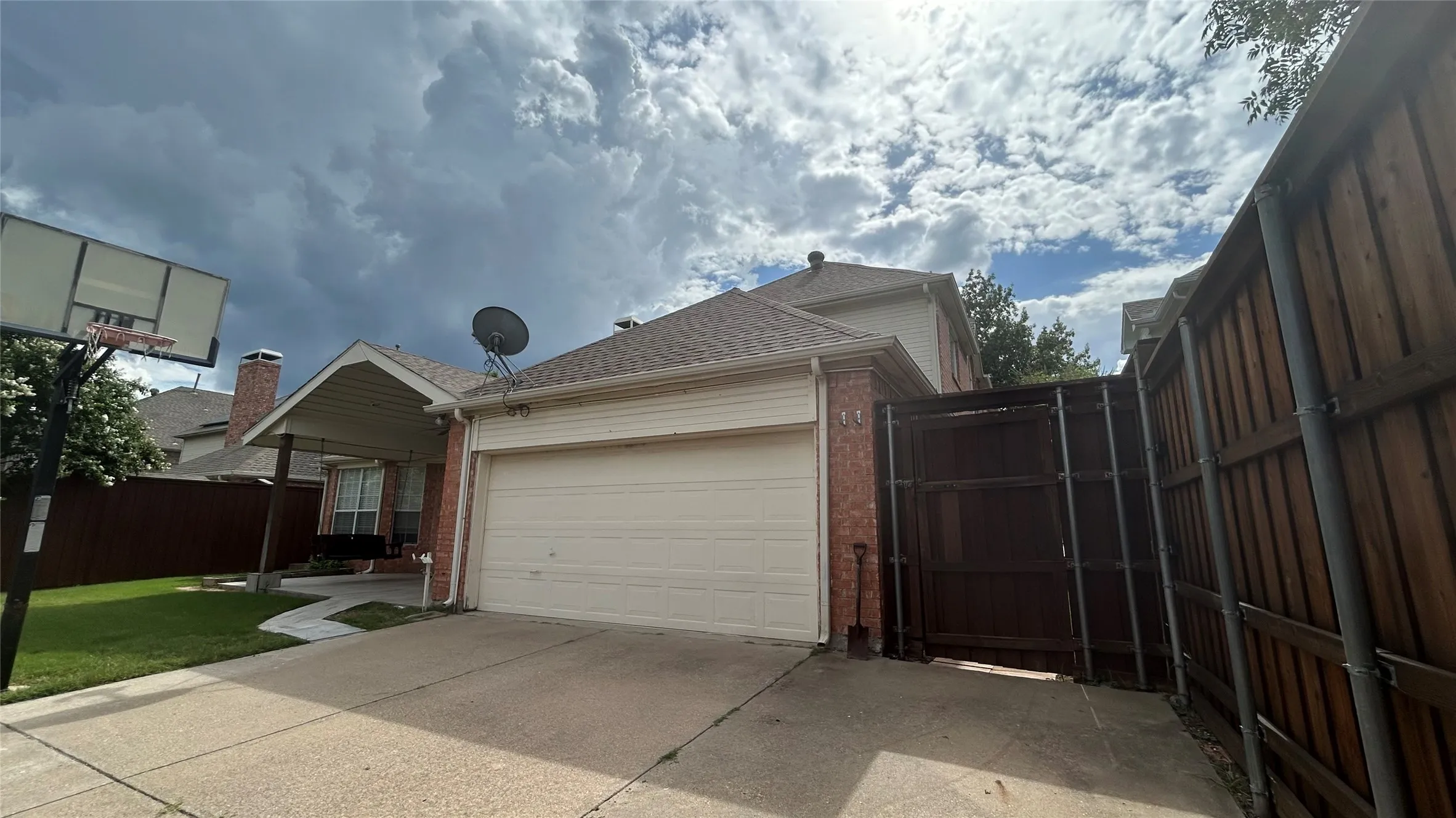Attached two-car garage with a paved driveway, brick facade, and a covered entryway