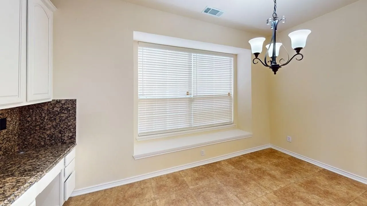 Built-in cabinetry with stone-look countertop, integrated window seating, decorative chandelier, and tile flooring