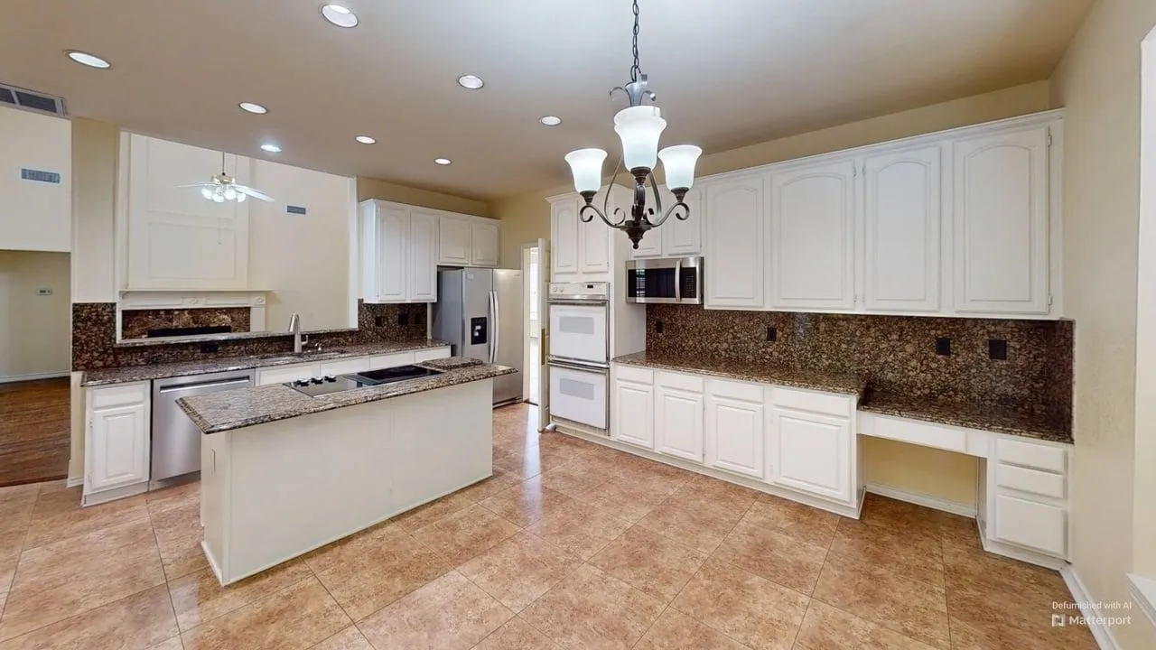 Kitchen featuring an island, integrated cooktop, double wall ovens, white cabinetry, and stone-look countertops with matching backsplash