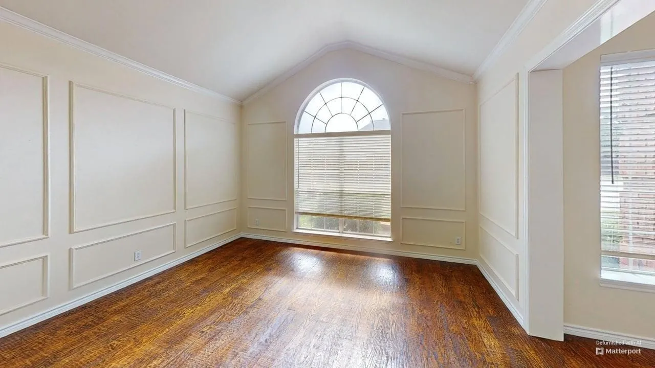Vaulted ceiling, wood-finish flooring, decorative wall paneling, arched window, and horizontal window blinds
