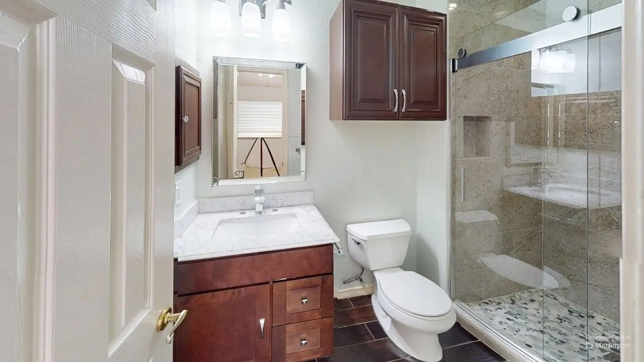 Vanity with white countertop, dark wood-finish cabinetry, and framed mirror
