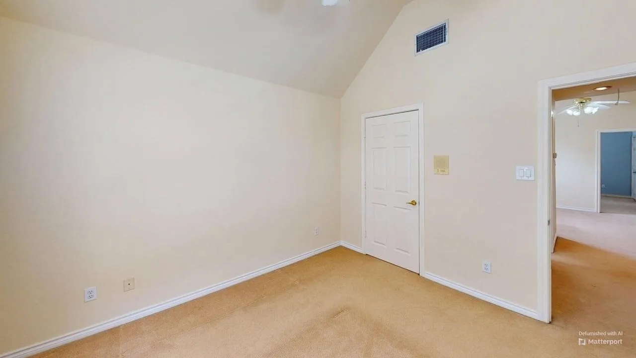 Vaulted ceiling with a ceiling fan, neutral carpet flooring, and a paneled door