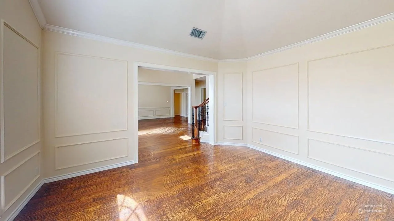 Hardwood-finish flooring, decorative wall paneling, crown molding, cased openings, and a staircase with a wood handrail
