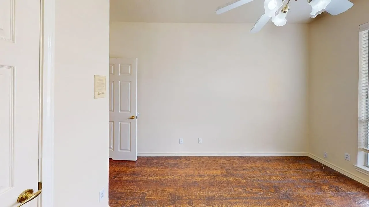 Wood-finish flooring with a ceiling fan and window with blinds