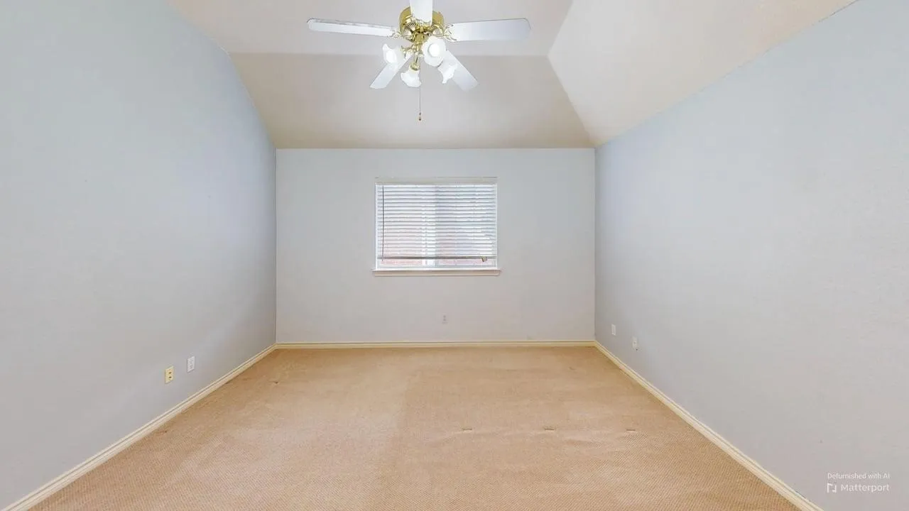 Vaulted ceiling with a ceiling fan light fixture, single window with blinds, and light-toned carpet flooring