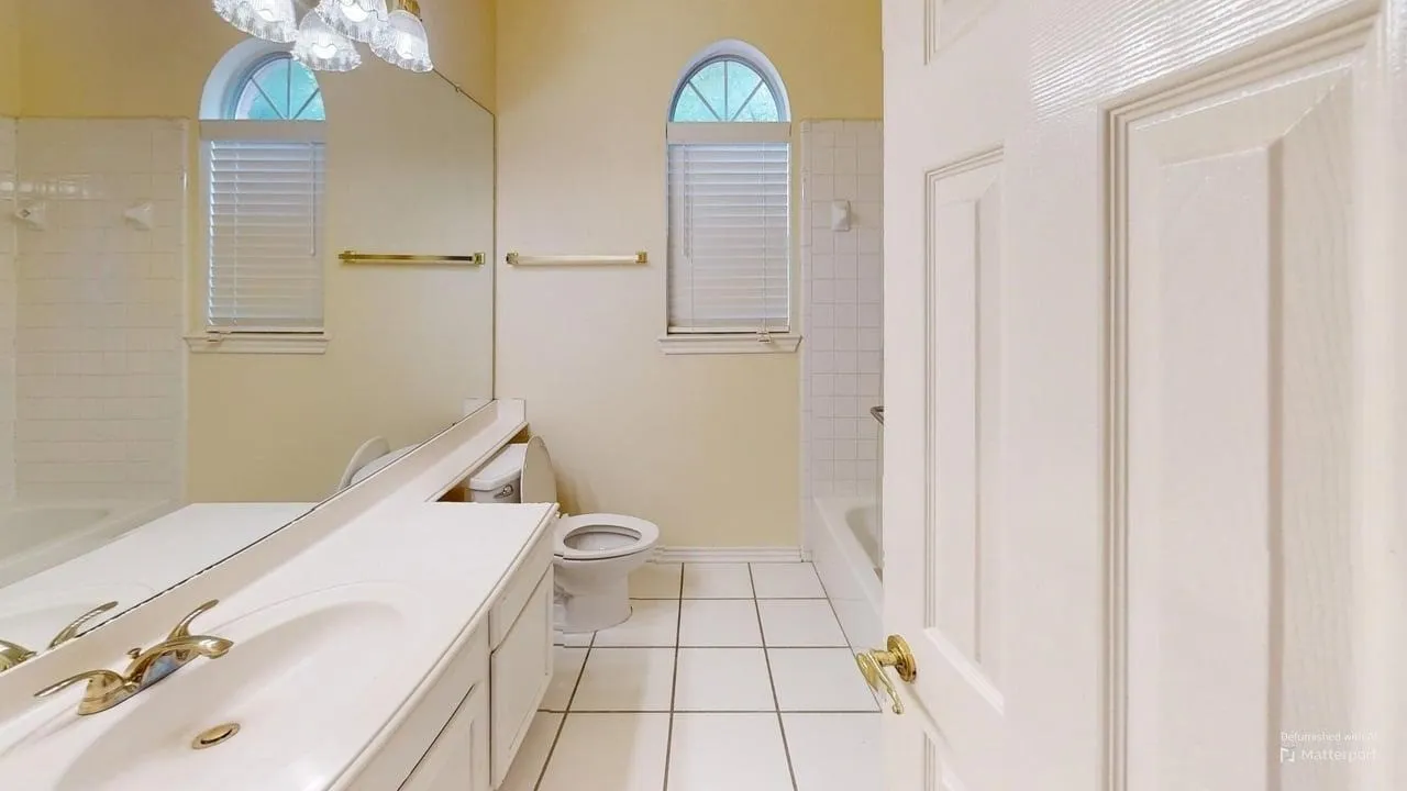 Bathroom with white tile flooring, arched windows, and a vanity with an integrated sink