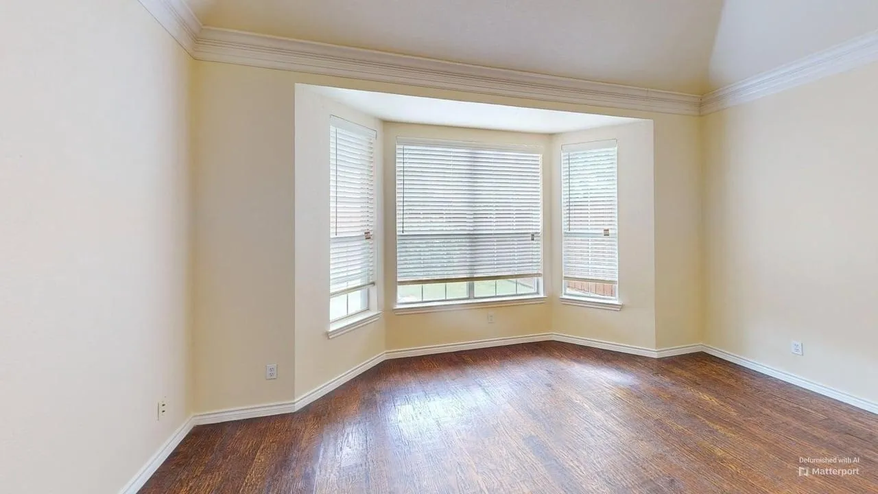 Bay window with multiple panels, wood-finish flooring, and crown molding
