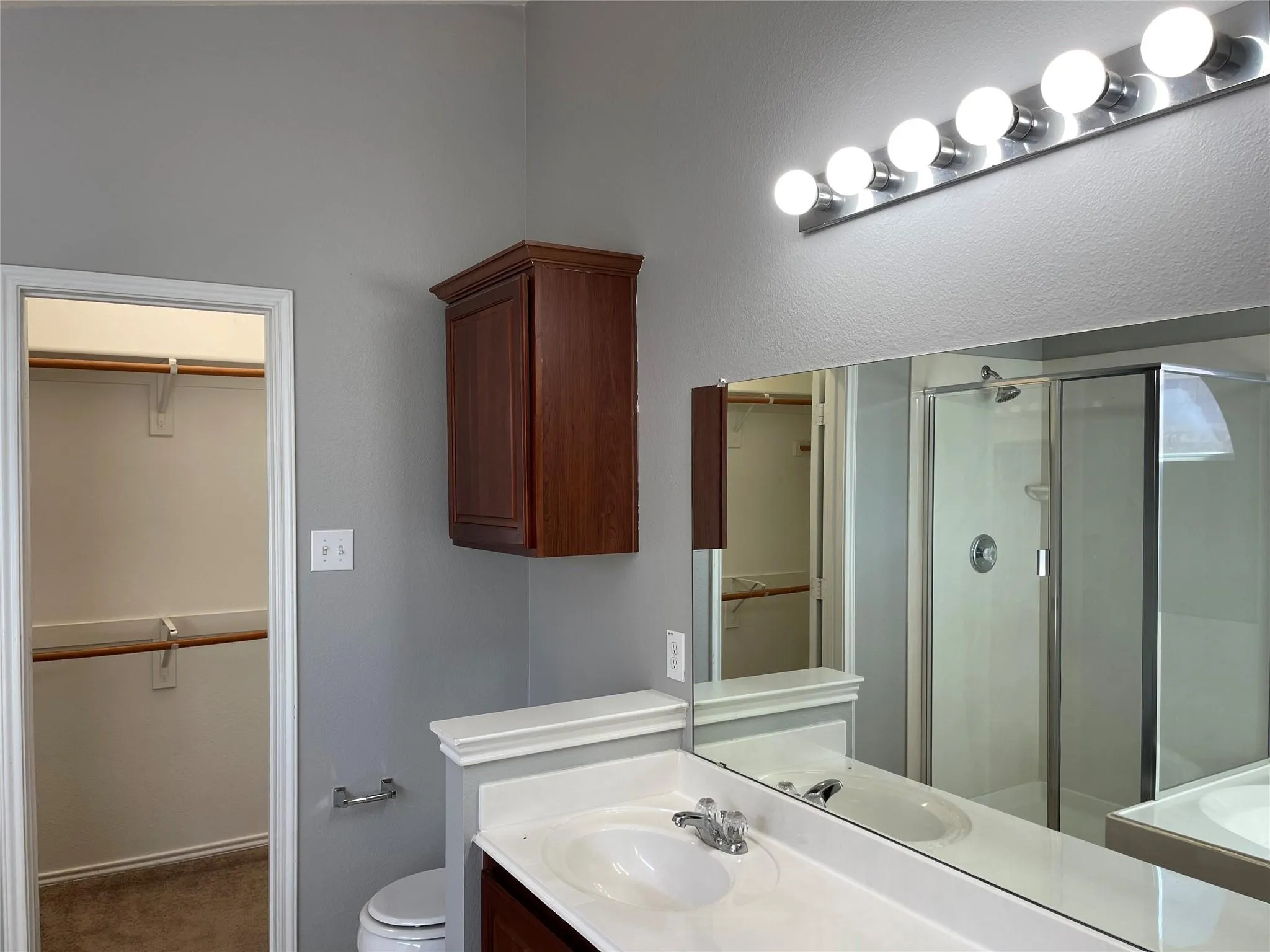 Vanity with integrated sink, chrome faucet, and expansive wall mirror