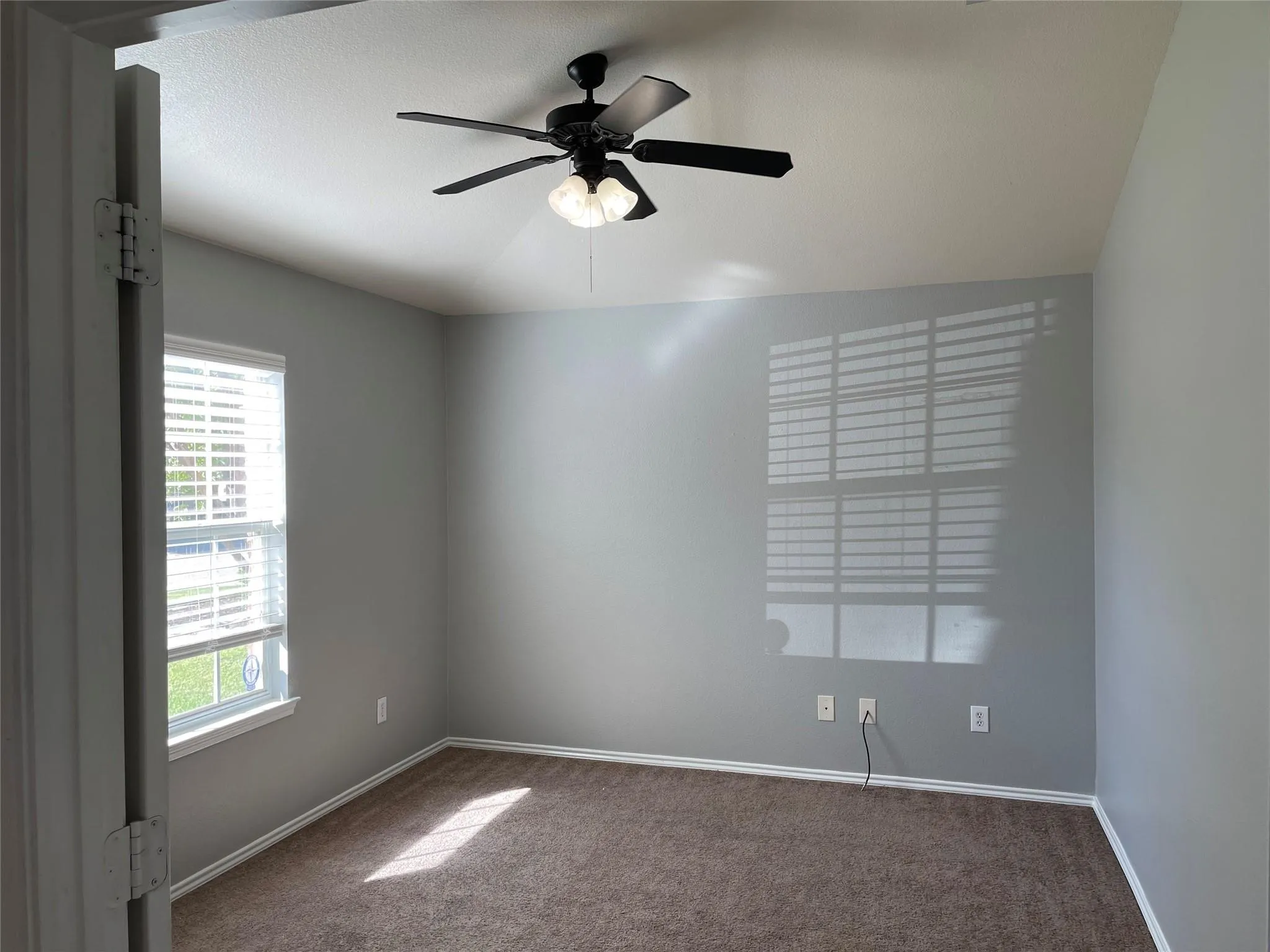 Carpeted flooring, ceiling fan with integrated lighting, window with blinds, and light gray wall paint