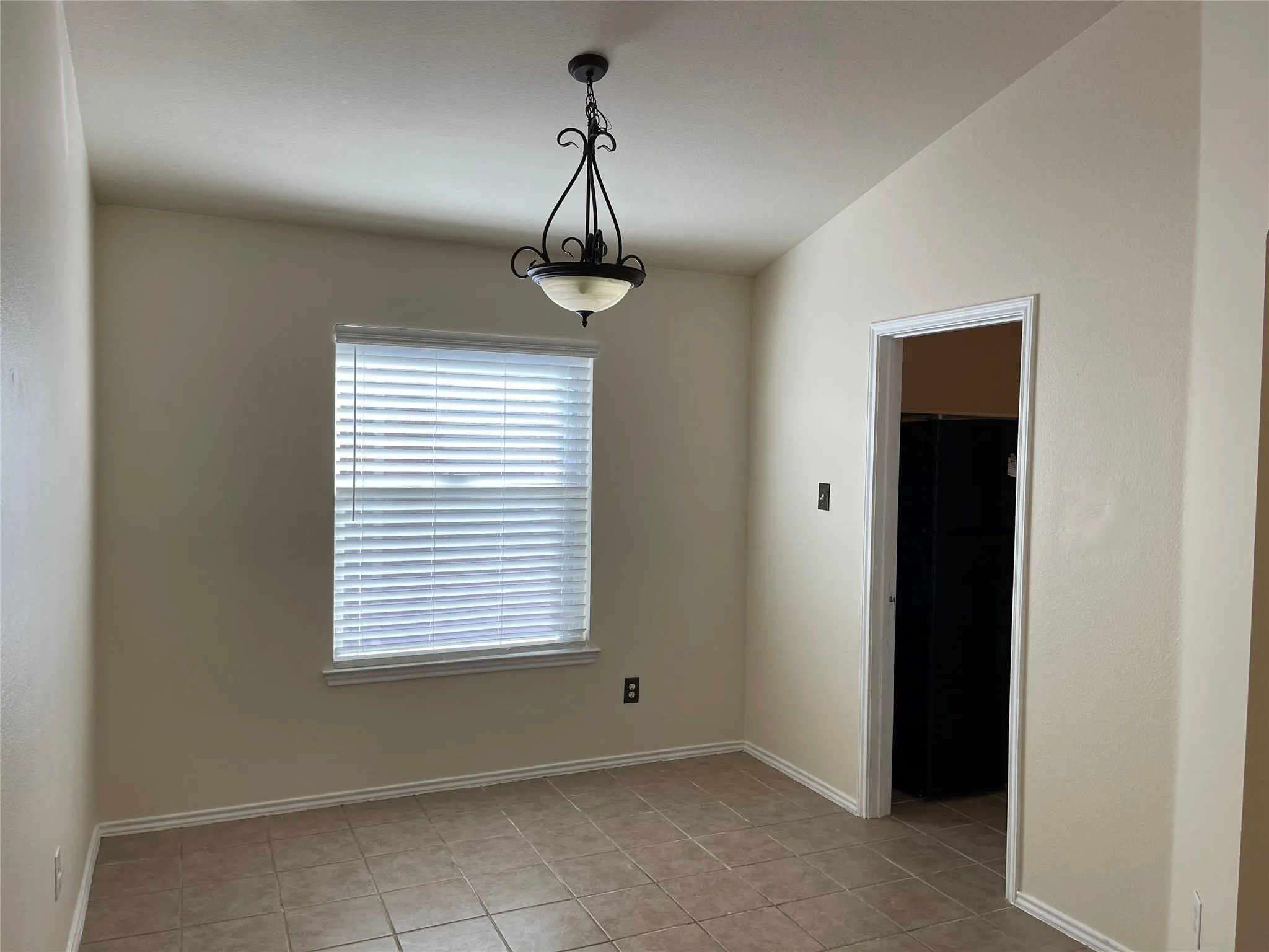 Tile flooring, window with blinds, ceiling-mounted light fixture, neutral wall paint, and white trim