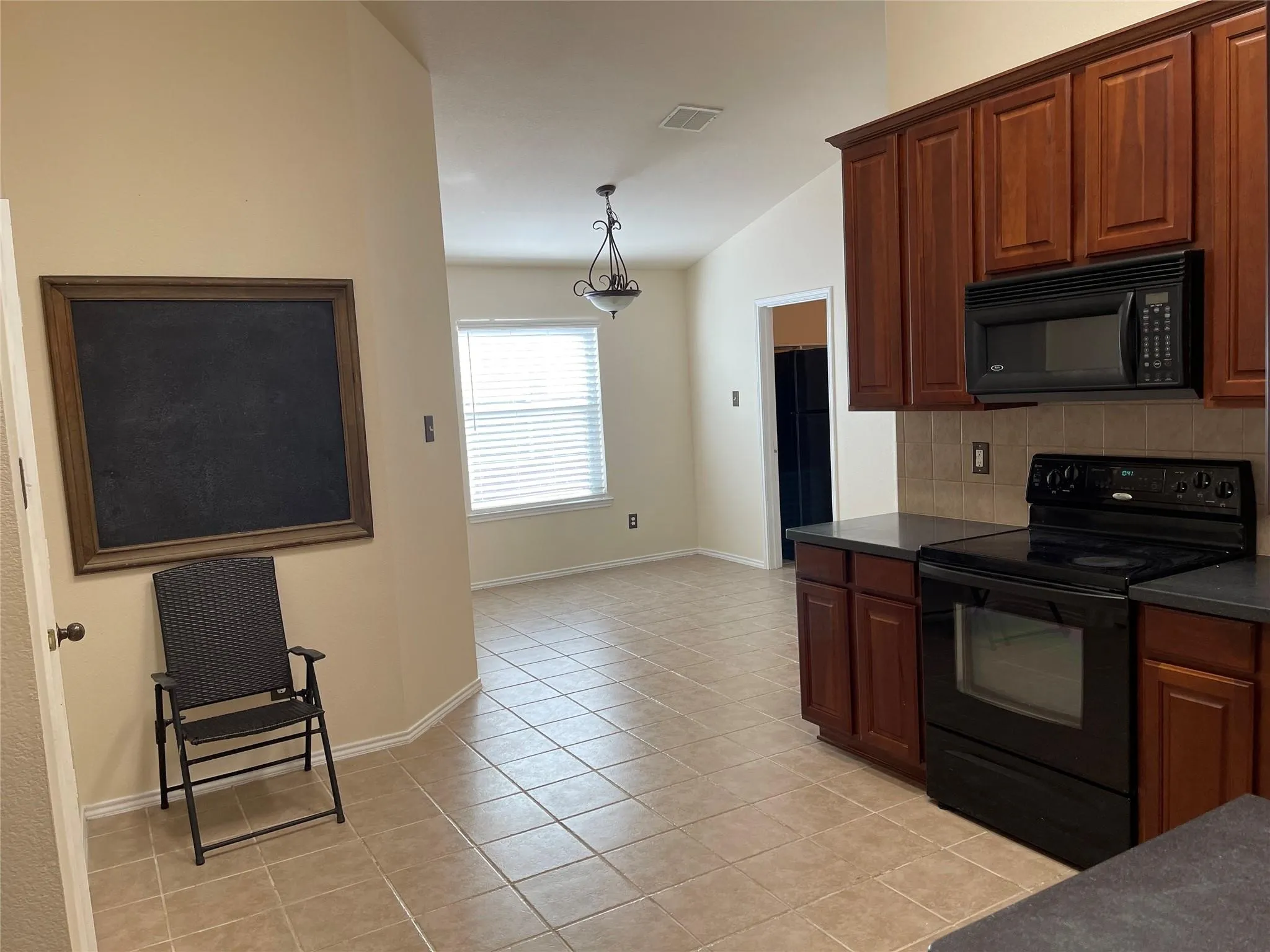 Kitchen featuring wood cabinetry, black appliances, tile flooring, and a tile backsplash