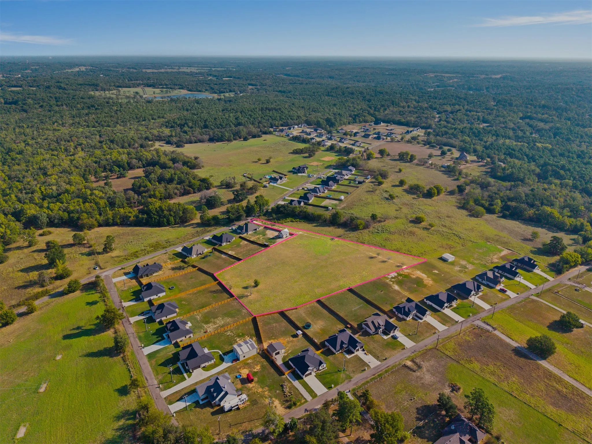 Expansive lot with defined boundaries within a developed residential area, featuring surrounding green spaces and mature trees