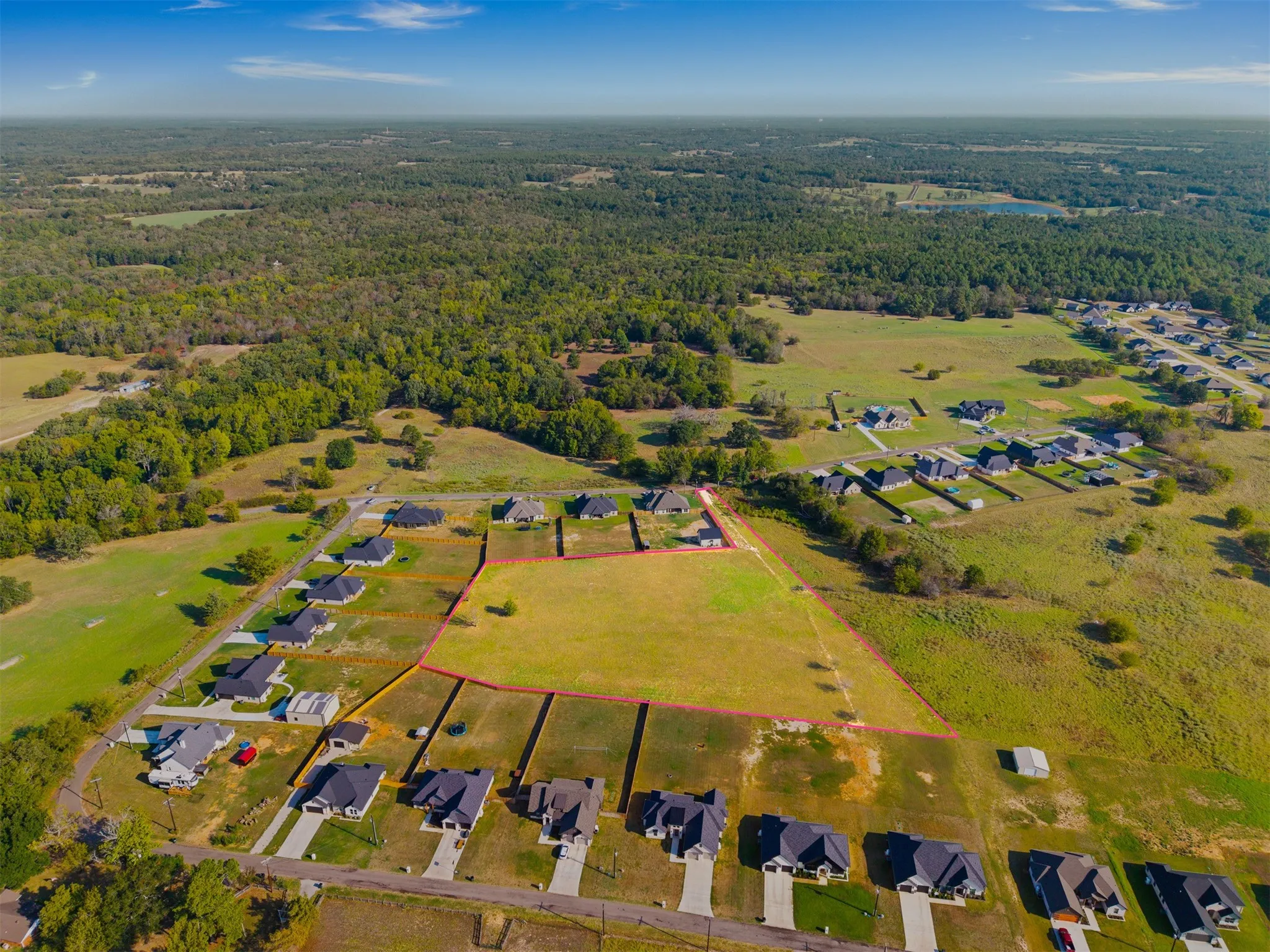 Expansive lot with surrounding developed properties, a clear land parcel, and established roadways