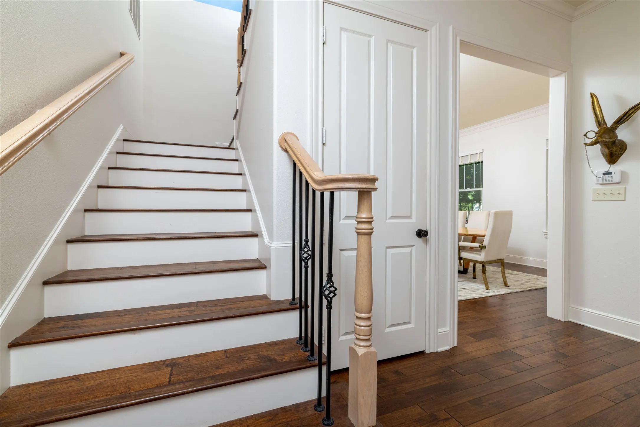 Hardwood flooring, painted risers, wood handrails, wrought iron balusters, and crown molding