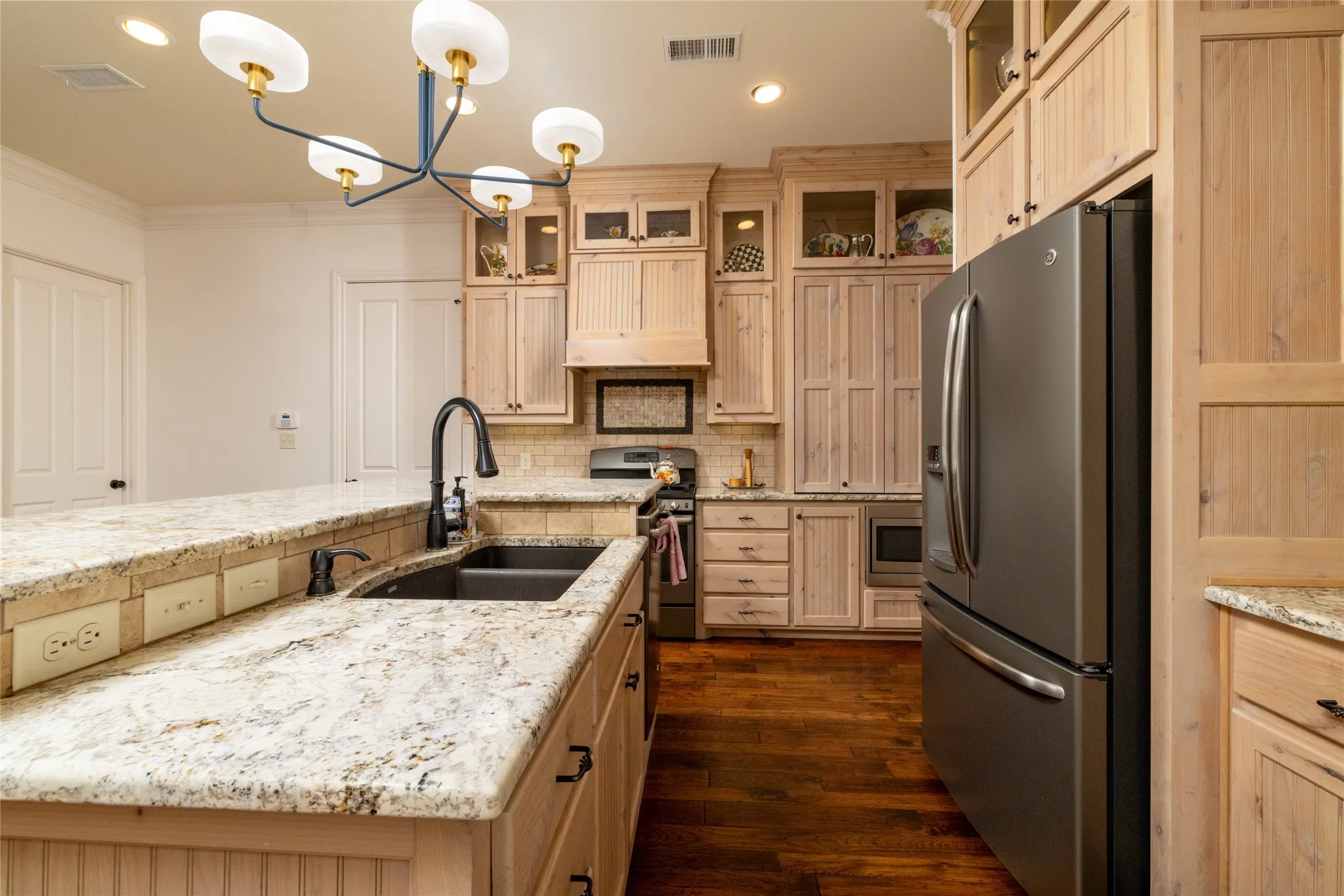 Wood-finish cabinetry with glass-front accents, dark wood-finish flooring, and granite countertops
