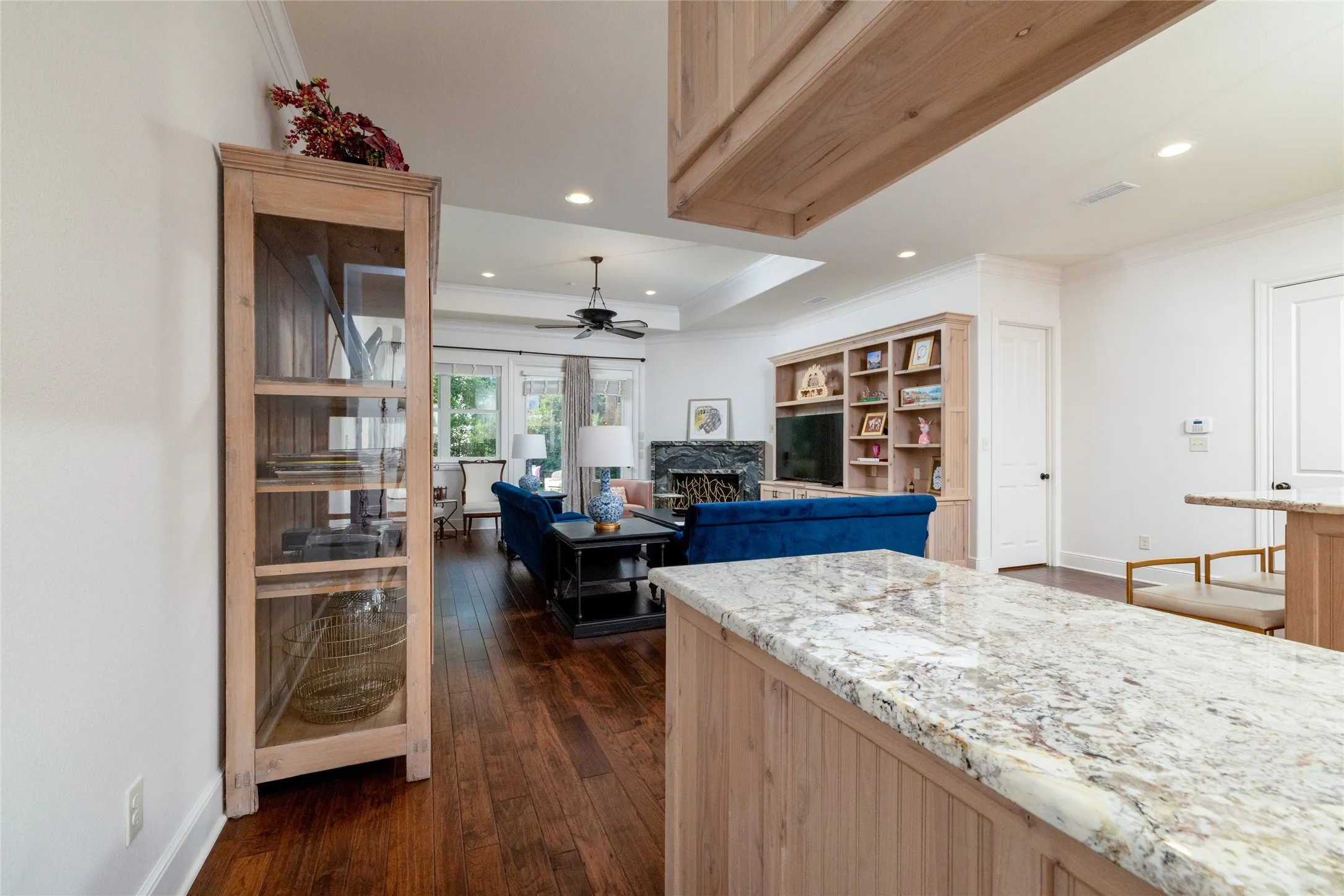Wood-finish flooring, recessed lighting, built-in shelving, a ceiling fan, and stone countertops