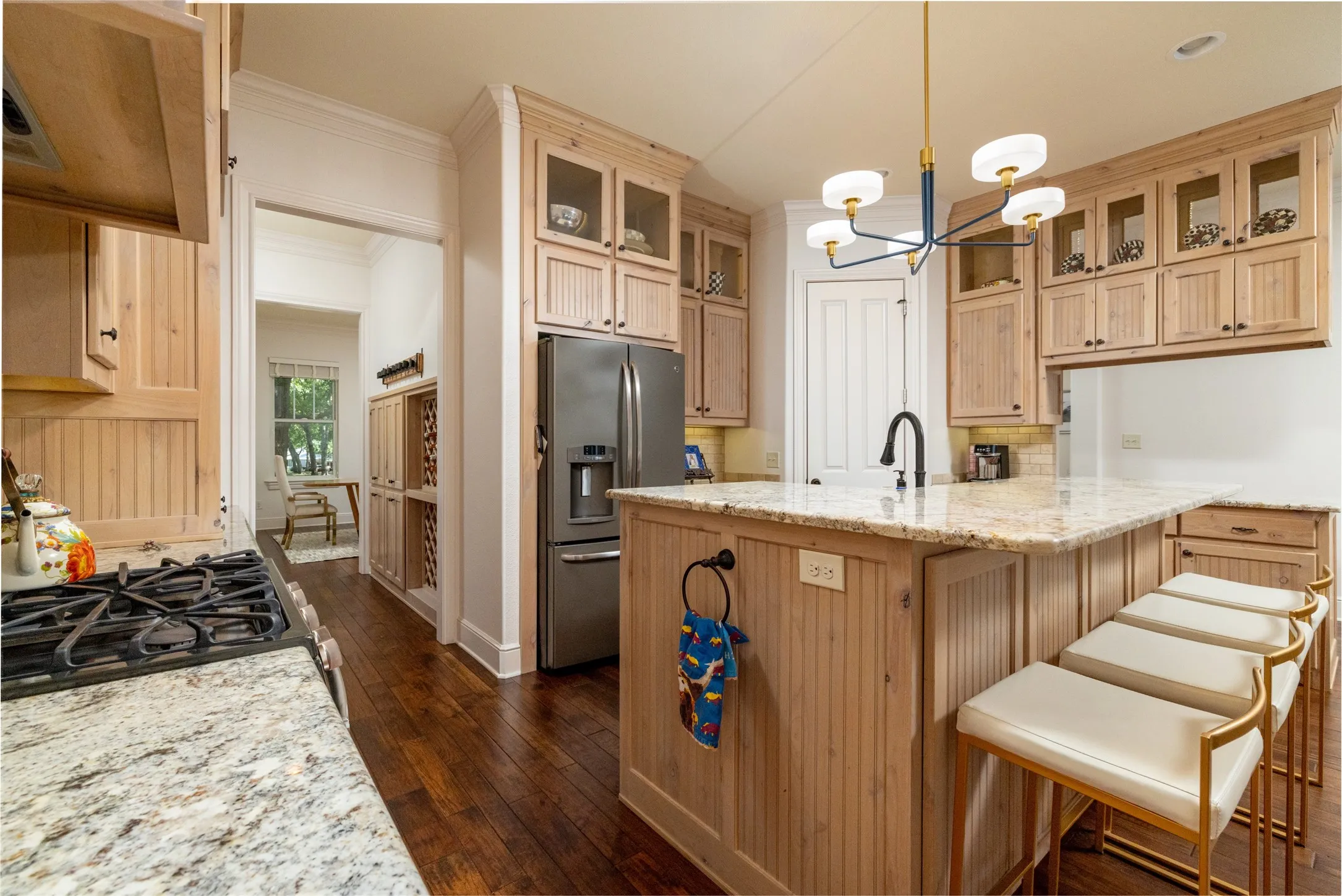 Kitchen featuring extensive light wood cabinetry, stone countertops, a stainless steel refrigerator, and a gas range