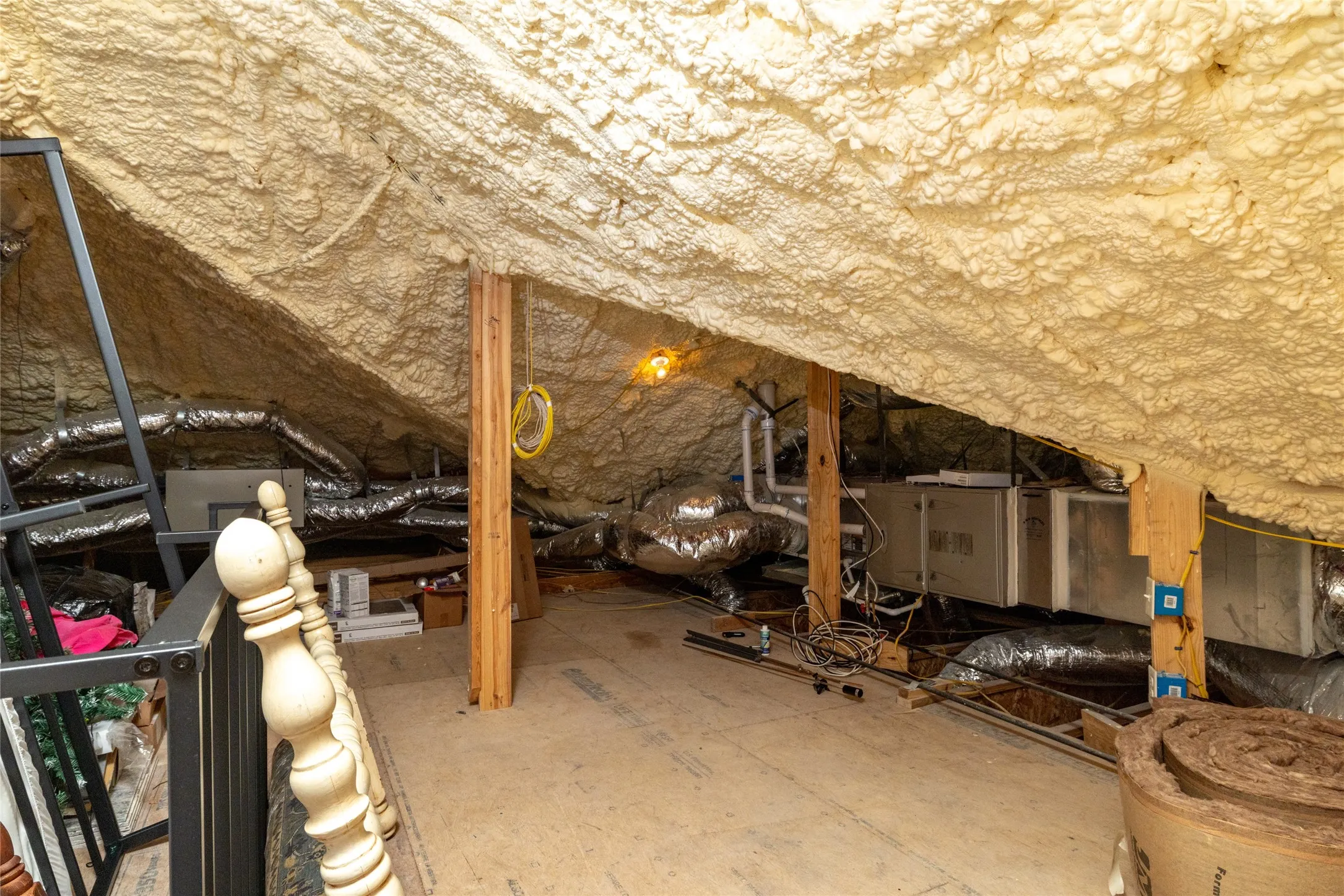 Attic space with spray foam insulation, exposed wooden beams, and HVAC ductwork