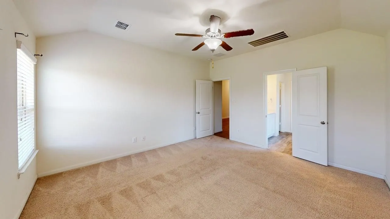 Vaulted ceiling with a ceiling fan, carpeted flooring, and window with blinds