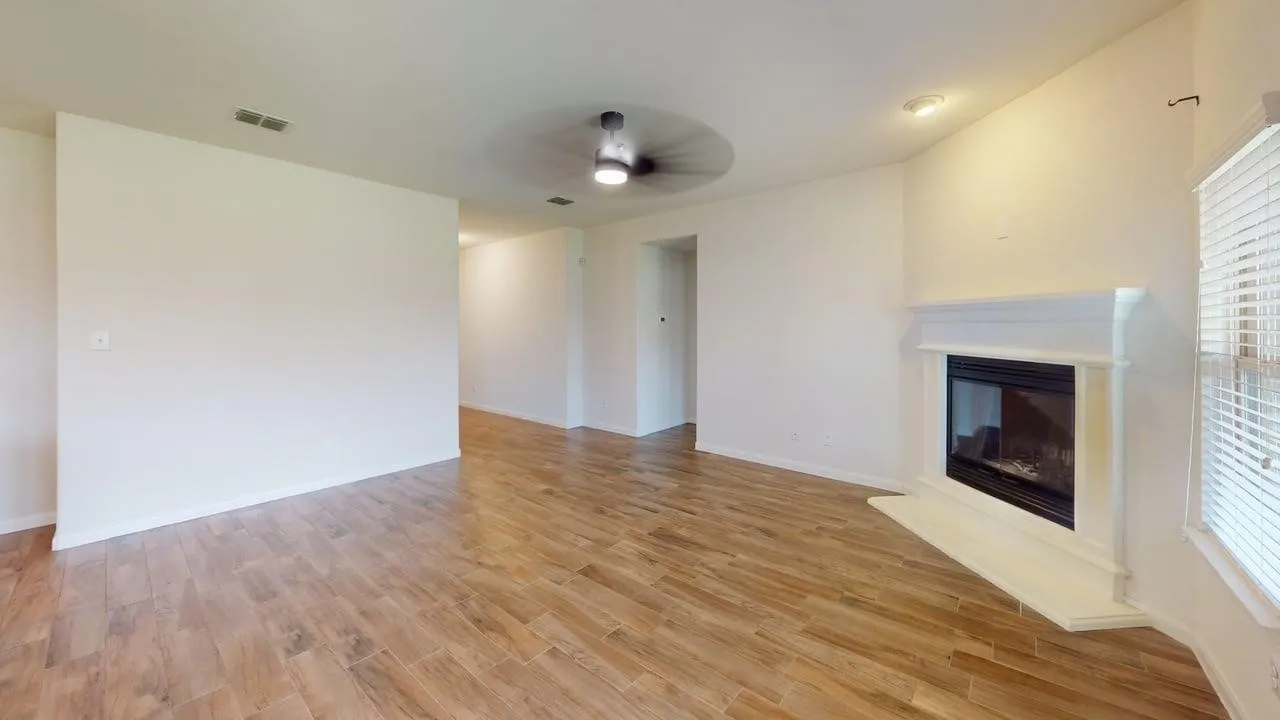 Living space featuring wood-finish flooring, a white mantel fireplace, and recessed lighting