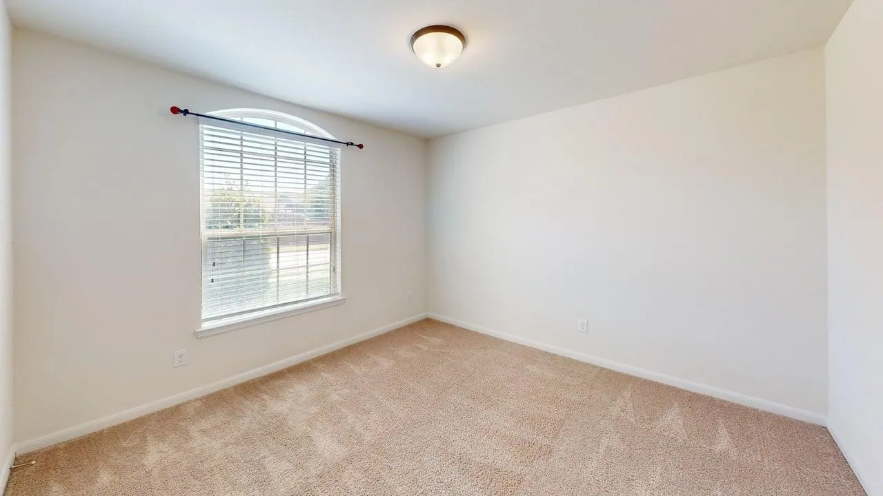 Arched window with blinds, carpeted flooring, neutral wall tones, and ceiling-mounted light fixture